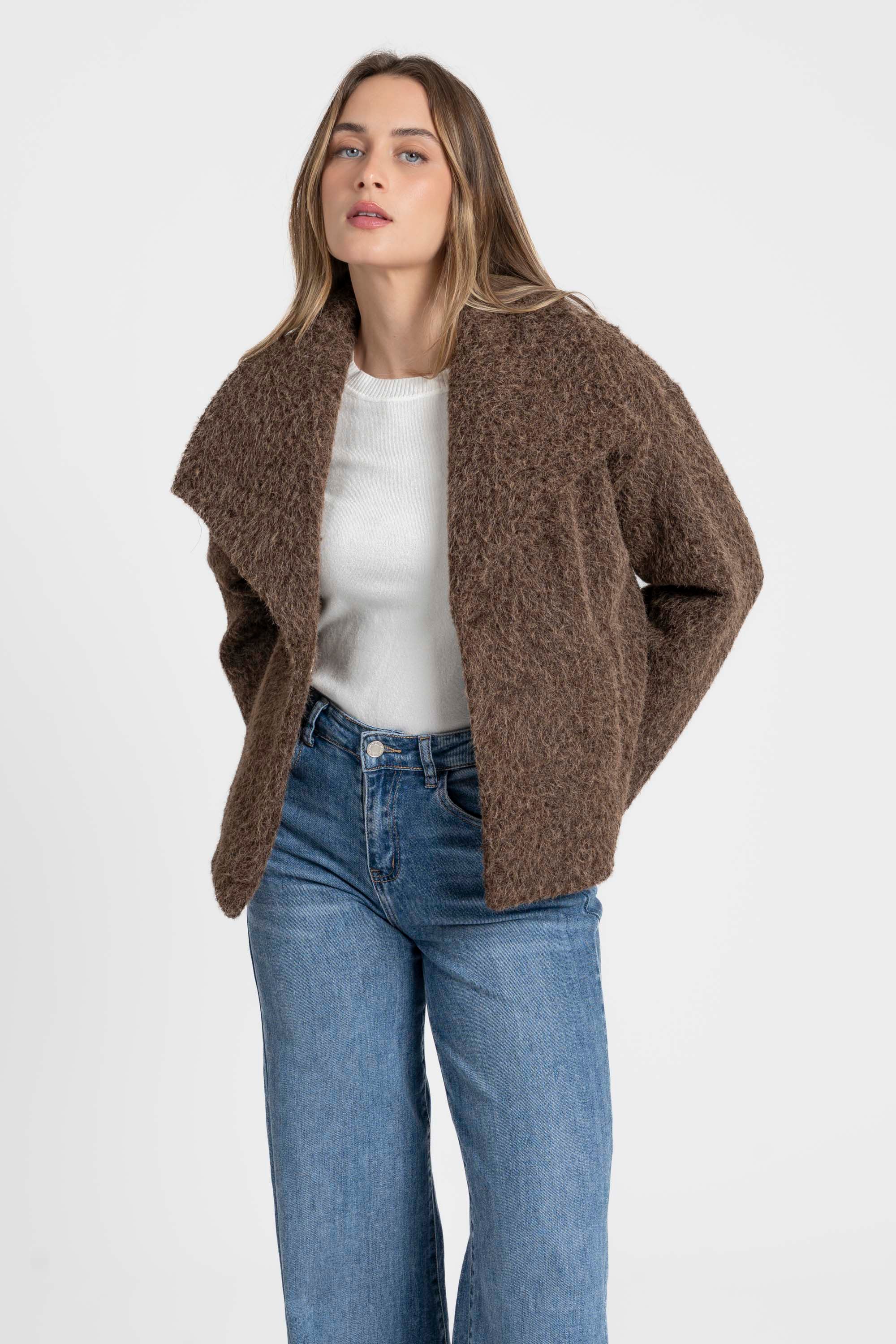 Femme souriante dans une veste courte effet poil doublée col à revers, associée à un jean, parfaite pour une tenue moderne. Veste courte femme.