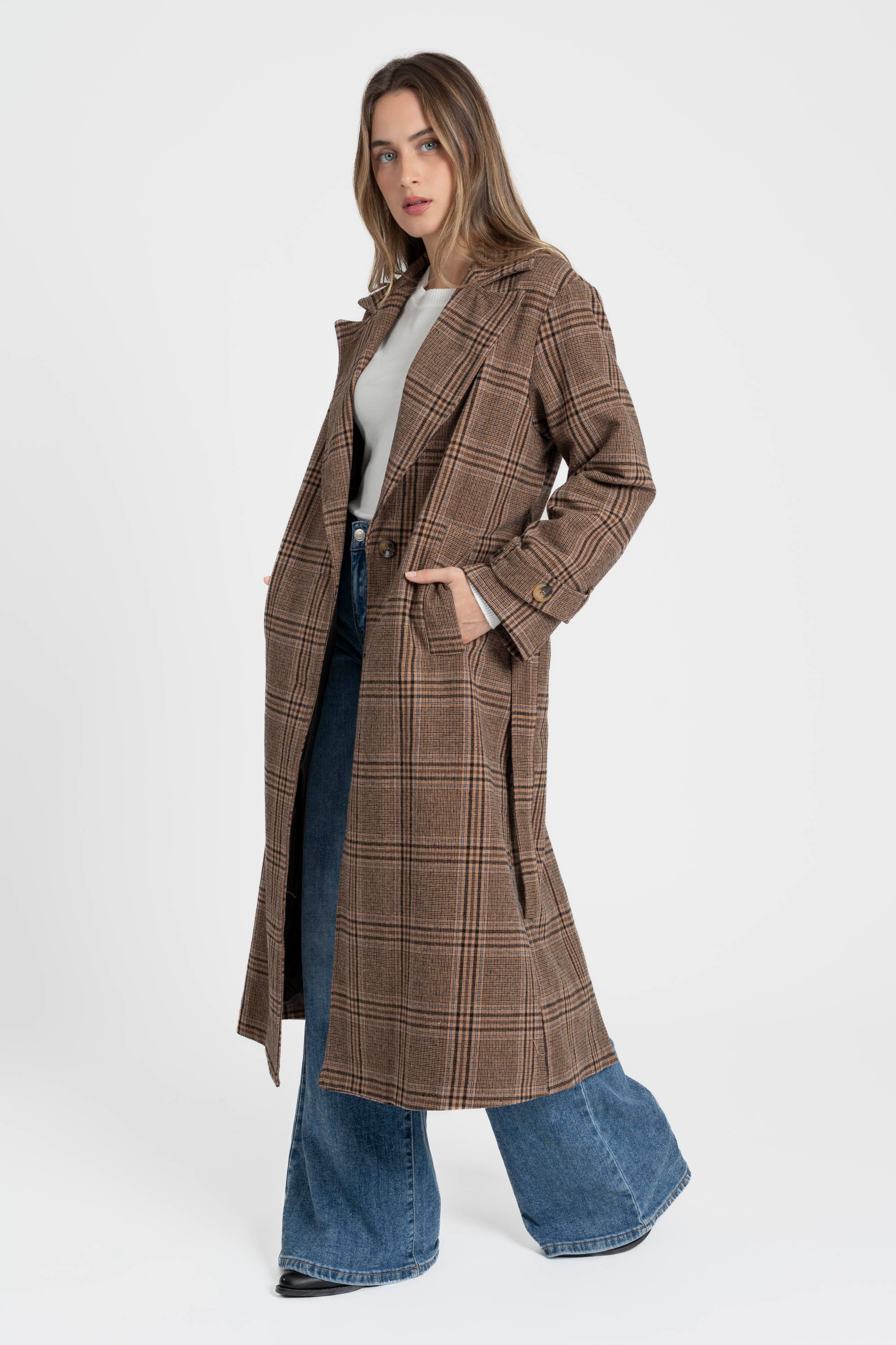 Manteau long femme en coton coupe ceinturée, porté par une femme qui pose en angle, montrant la longueur et la structure élégante du manteau.