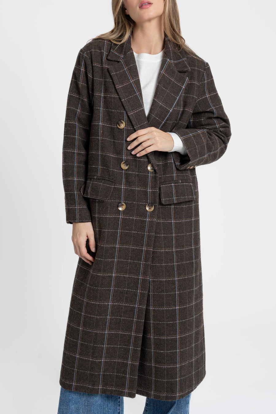 Gros plan sur une femme tenant un manteau long croisé marron en coton mélangé, mettant en avant les détails des boutons et la texture du tissu. Manteau long croisé femme en coton mélangé marron.