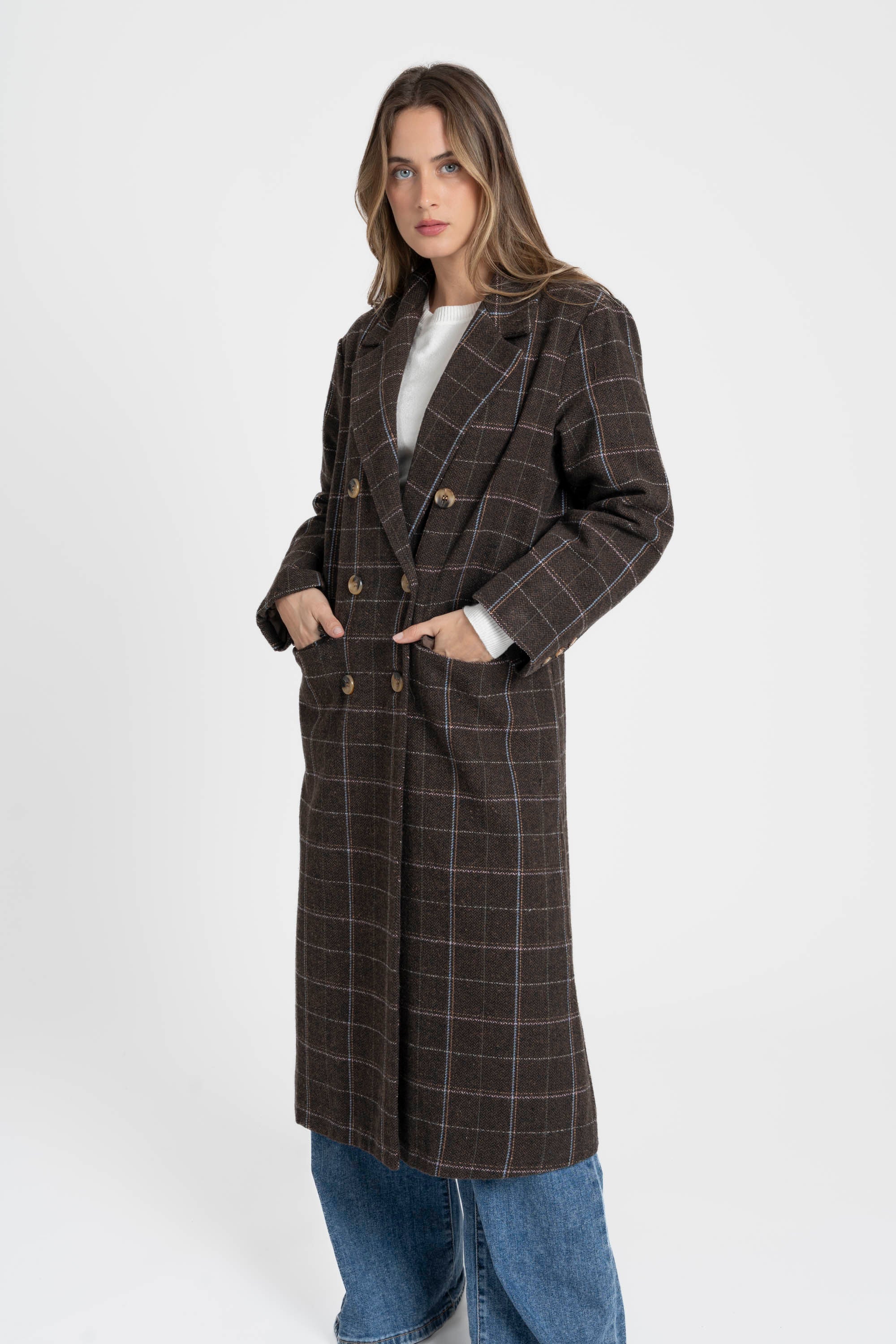 Femme posant dans un manteau long croisé marron en coton mélangé, avec les mains dans les poches, illustrant le style chic et décontracté. Manteau long croisé femme en coton mélangé marron.