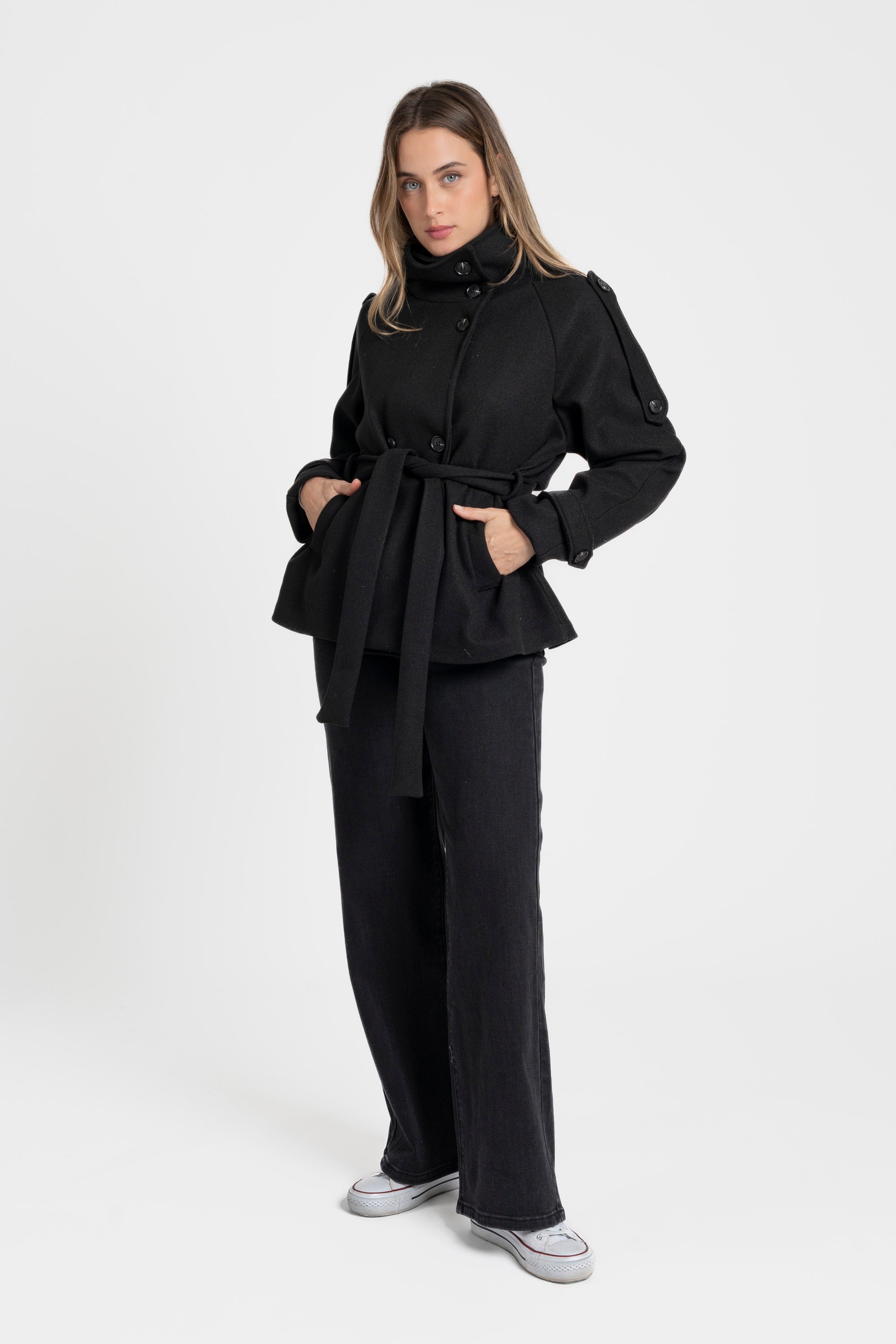 Modèle en pantalon noir posant dans une veste femme col montant coupe droite, mettant en avant la silhouette raffinée de la pièce.