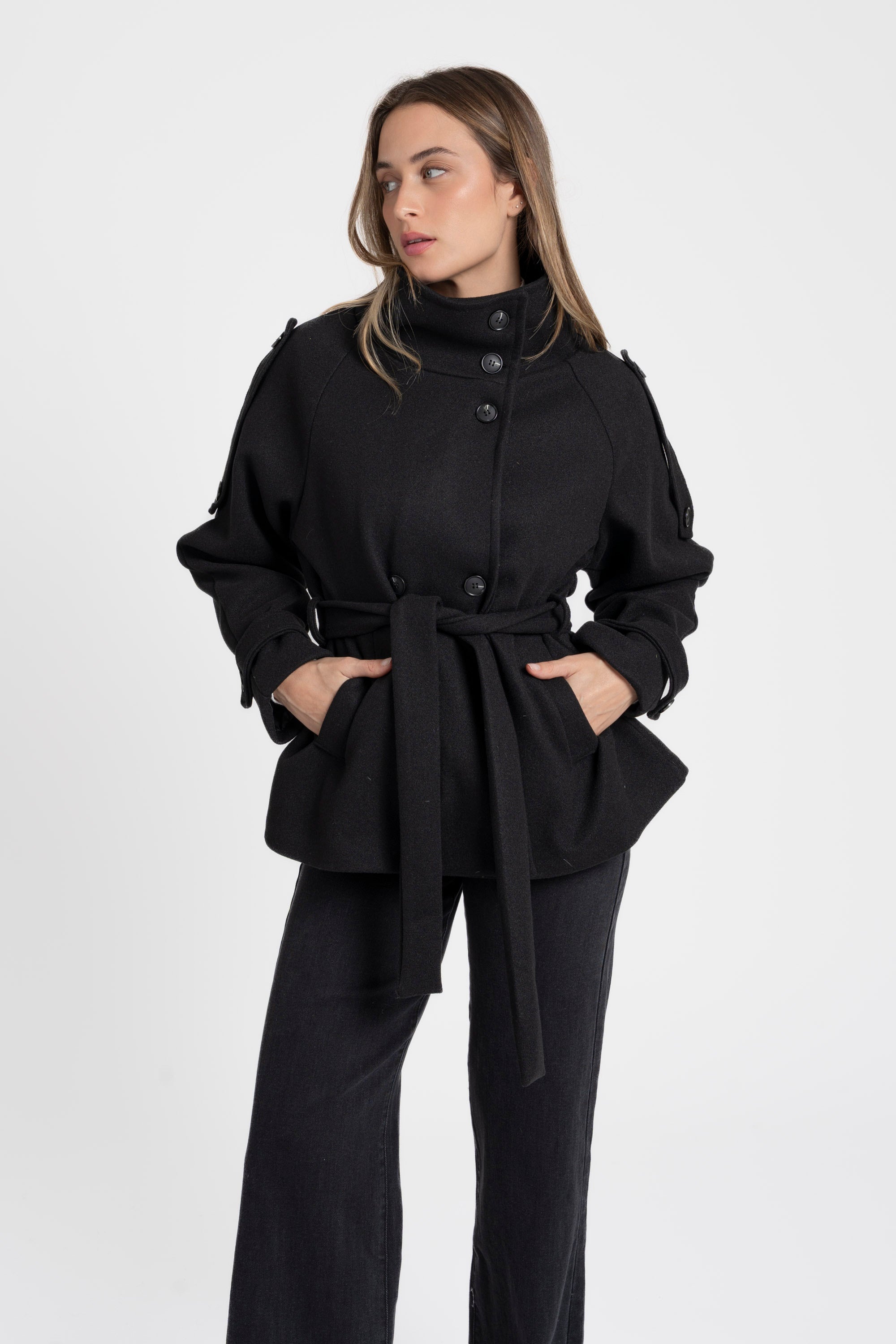 Modèle portant une veste femme col montant coupe droite en noir avec ceinture, parfaite pour le style chic et décontracté.