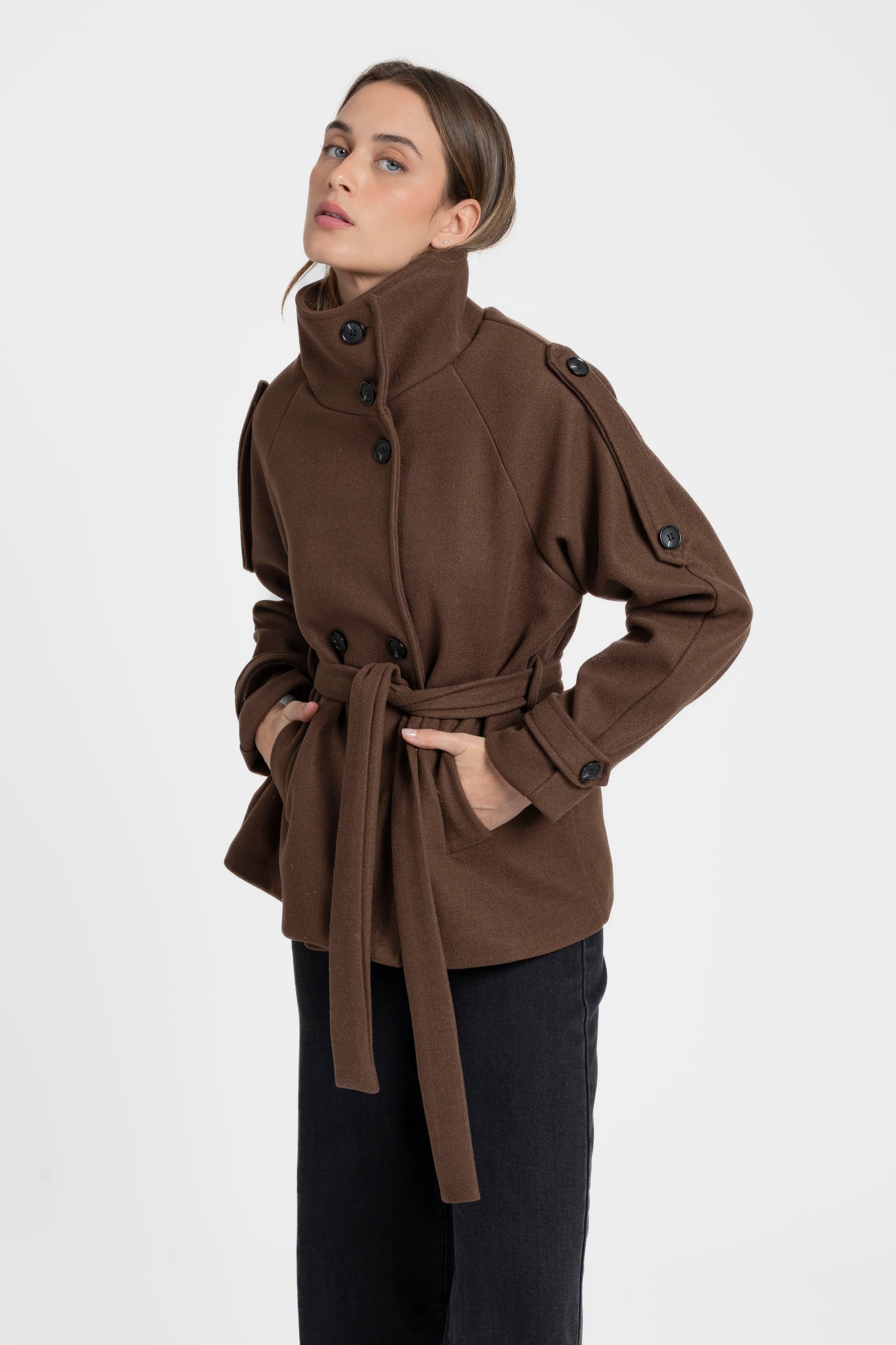 Femme dans une veste femme col montant coupe droite marron, associe élégance et confort avec une ceinture à la taille.