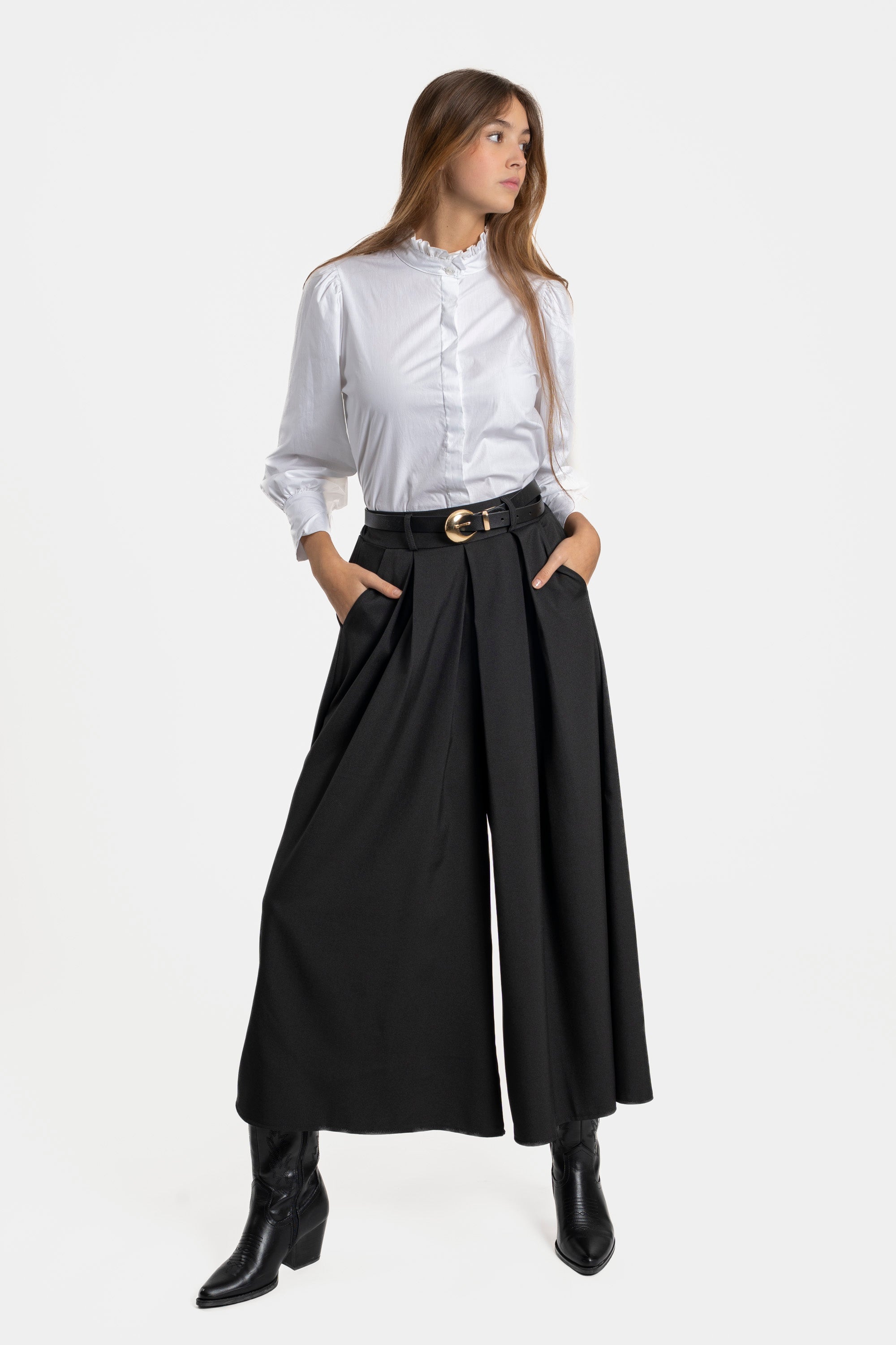 Femme enceinte de chic avec un pantalon fluide taille haute femme noir, portant une chemise blanche, pose élégante et féminine.