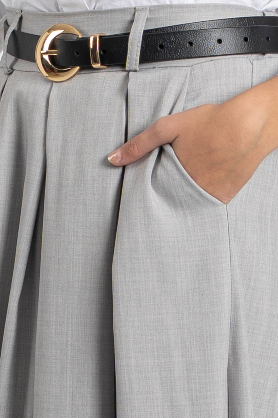 Focus sur le pantalon fluide taille haute femme gris, montrant une main dans la poche avec une ceinture décorative.
