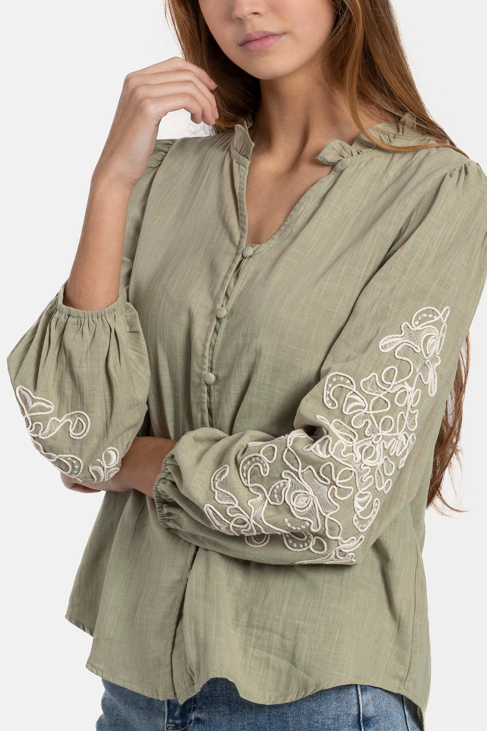 Détail d'une femme avec une chemise brodée en coton, mettant en avant les broderies sur les manches. Chemise brodée femme pour un look sophistiqué.