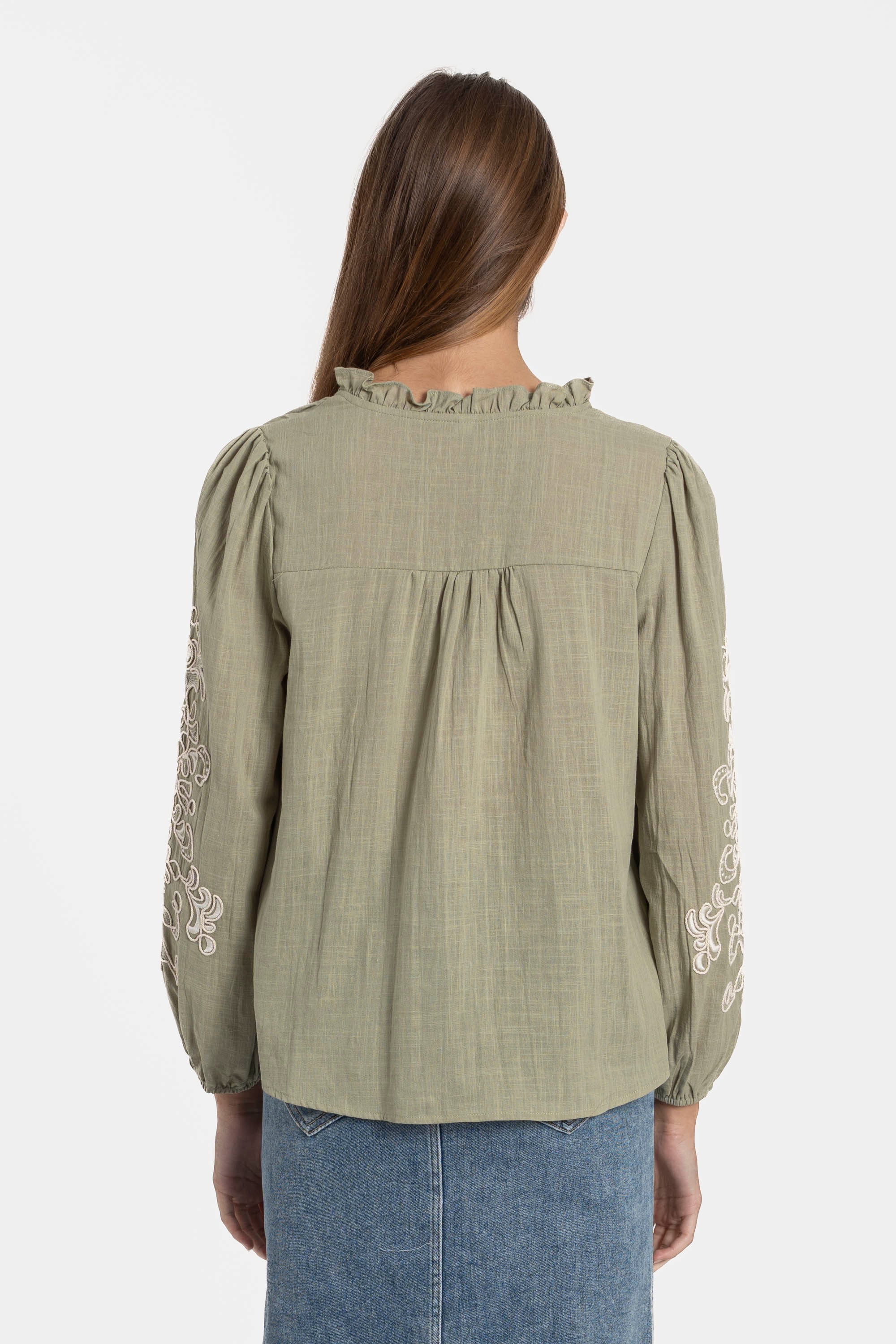 Vue arrière d'une femme en chemise brodée en coton, mettant en avant le détail de la coupe et des broderies. Chemise brodée femme confortable et stylée.