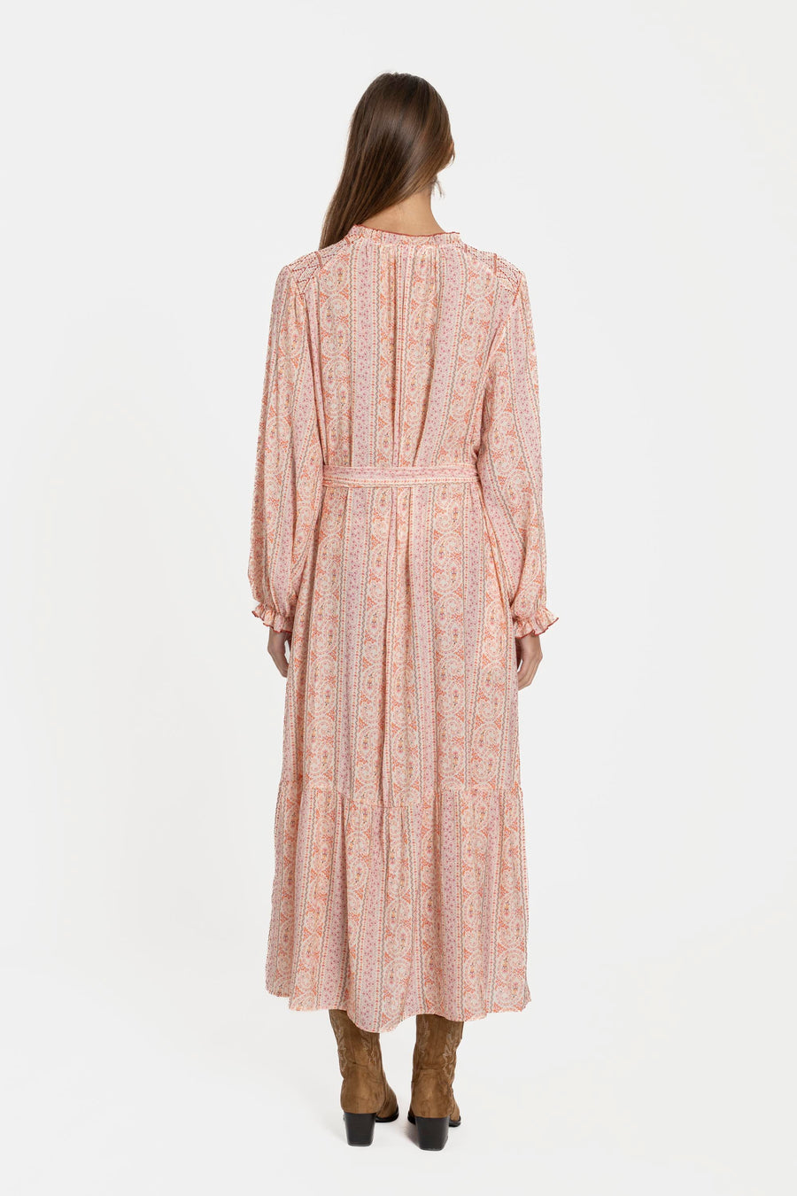 Vue arrière d'une femme dans une robe longue fluide imprimée avec ceinture rose, soulignant sa coupe fluide et élégante.
