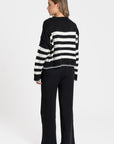 Ensemble maille rayée femme : modèle noir à rayures blanches avec un look décontracté.