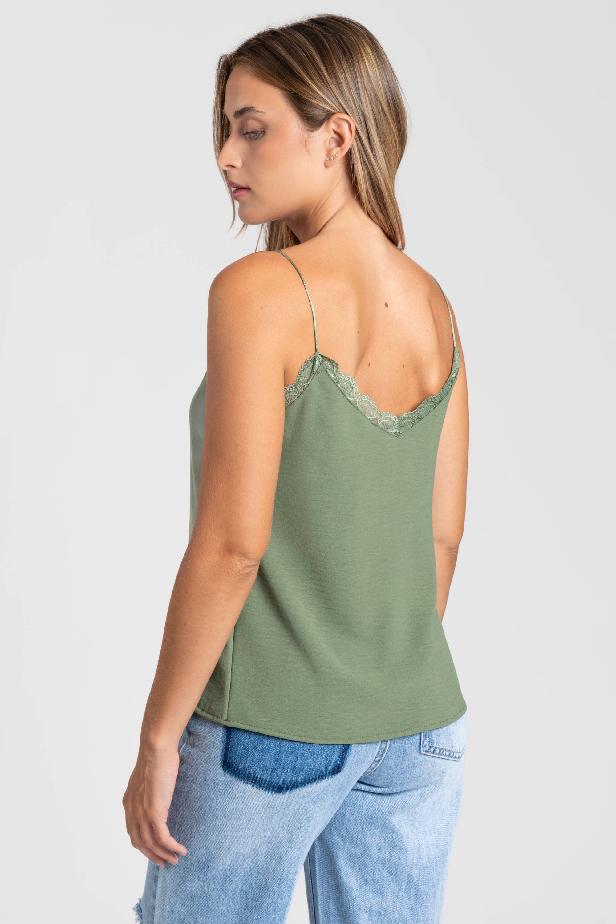 Femme montrant le top en mousseline femme fluide à bretelles avec dentelle verte, en position frontale.