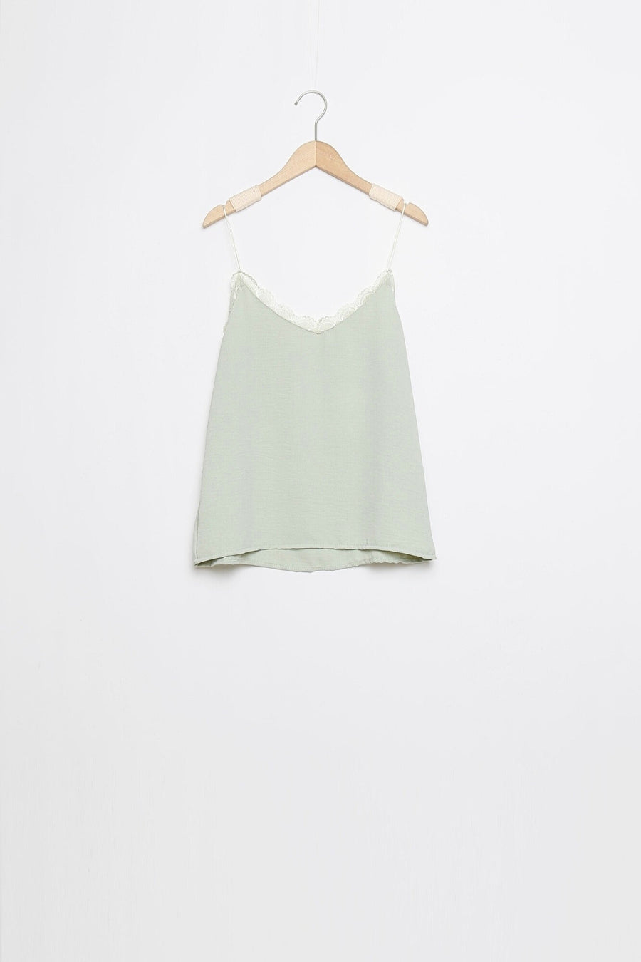 Top en mousseline femme fluide à bretelles avec dentelle vert clair, suspendu pour un aperçu de la coupe.