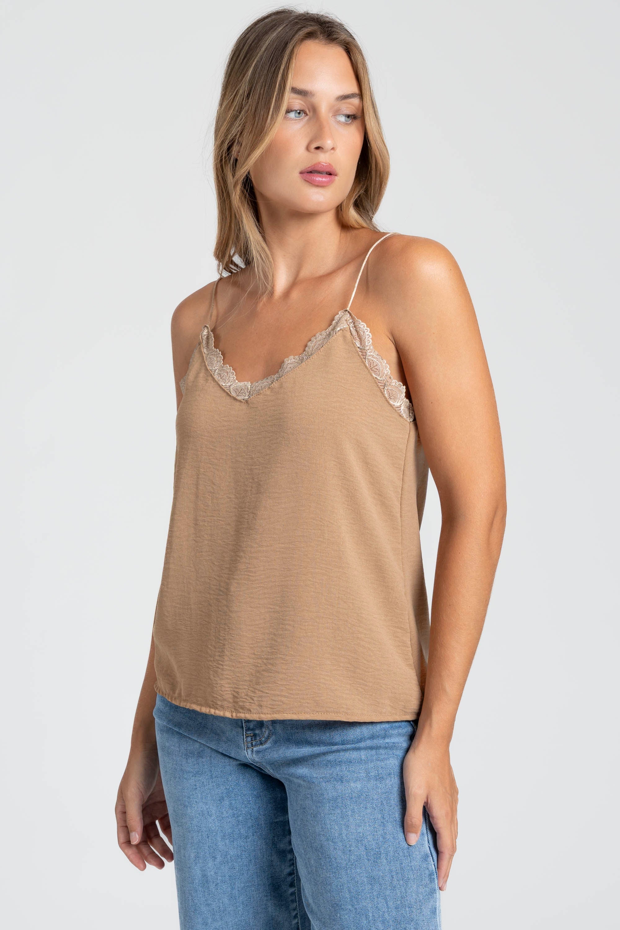 Femme portant un top en mousseline femme fluide à bretelles avec dentelle beige, look estival décontracté.