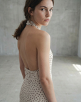 Vue arrière d'une femme dans une robe midi imprimée écru à pois, col halter décolleté plongeant, montrant un dos nu.