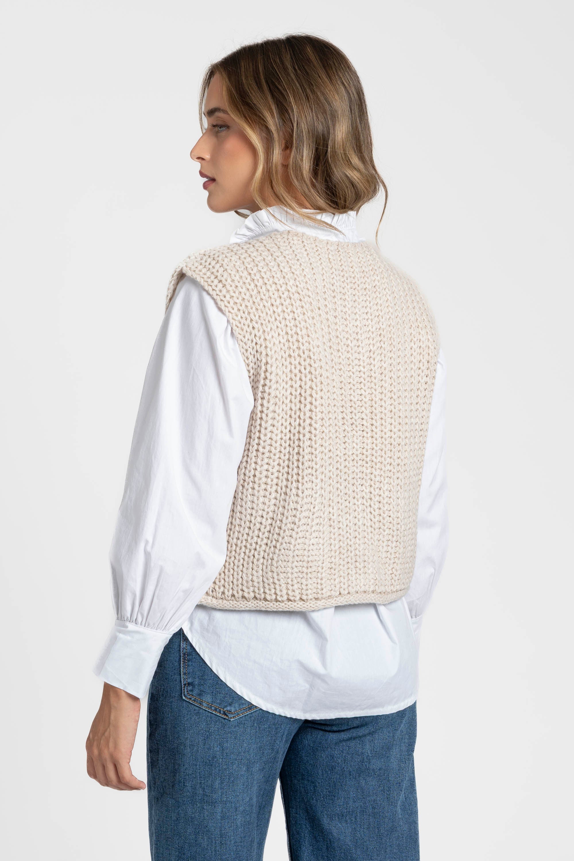 Garde-robe féminine avec gilet sans manches en maille femme crème, vu de dos, idéal pour la superposition. Gilet maille femme.