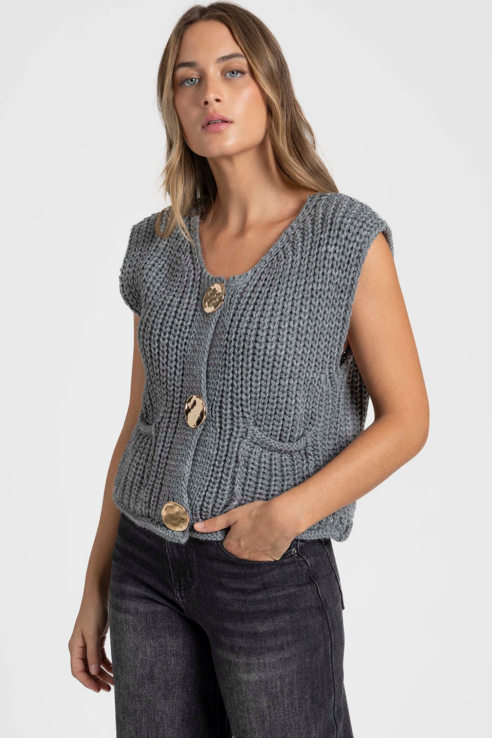 Gilet sans manches en maille femme couleur gris, affichant des boutons métalliques, porté pour un look élégant et moderne. Gilet maille femme.