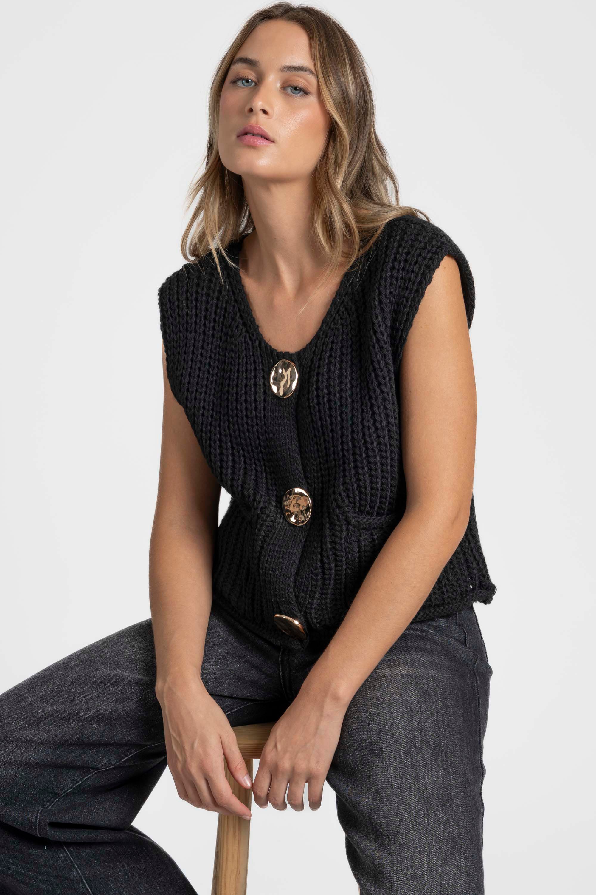 Modèle élégant en gilet sans manches en maille femme noir, avec boutons métalliques pour un look tendance. Gilet maille femme.