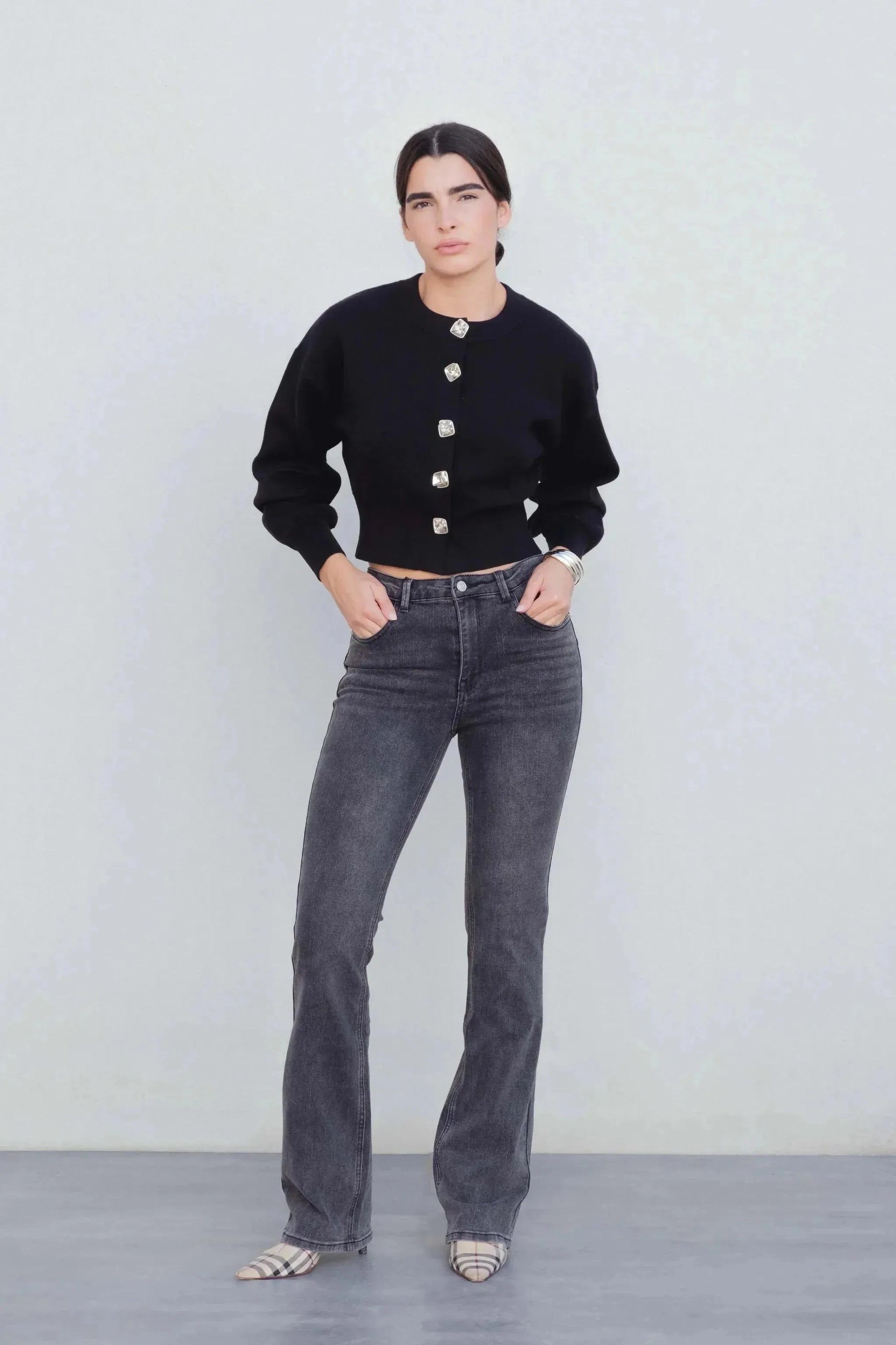 Modèle de jean femme gris évasé, confortable et tendance, porté avec un pull noir, parfait pour toute occasion.