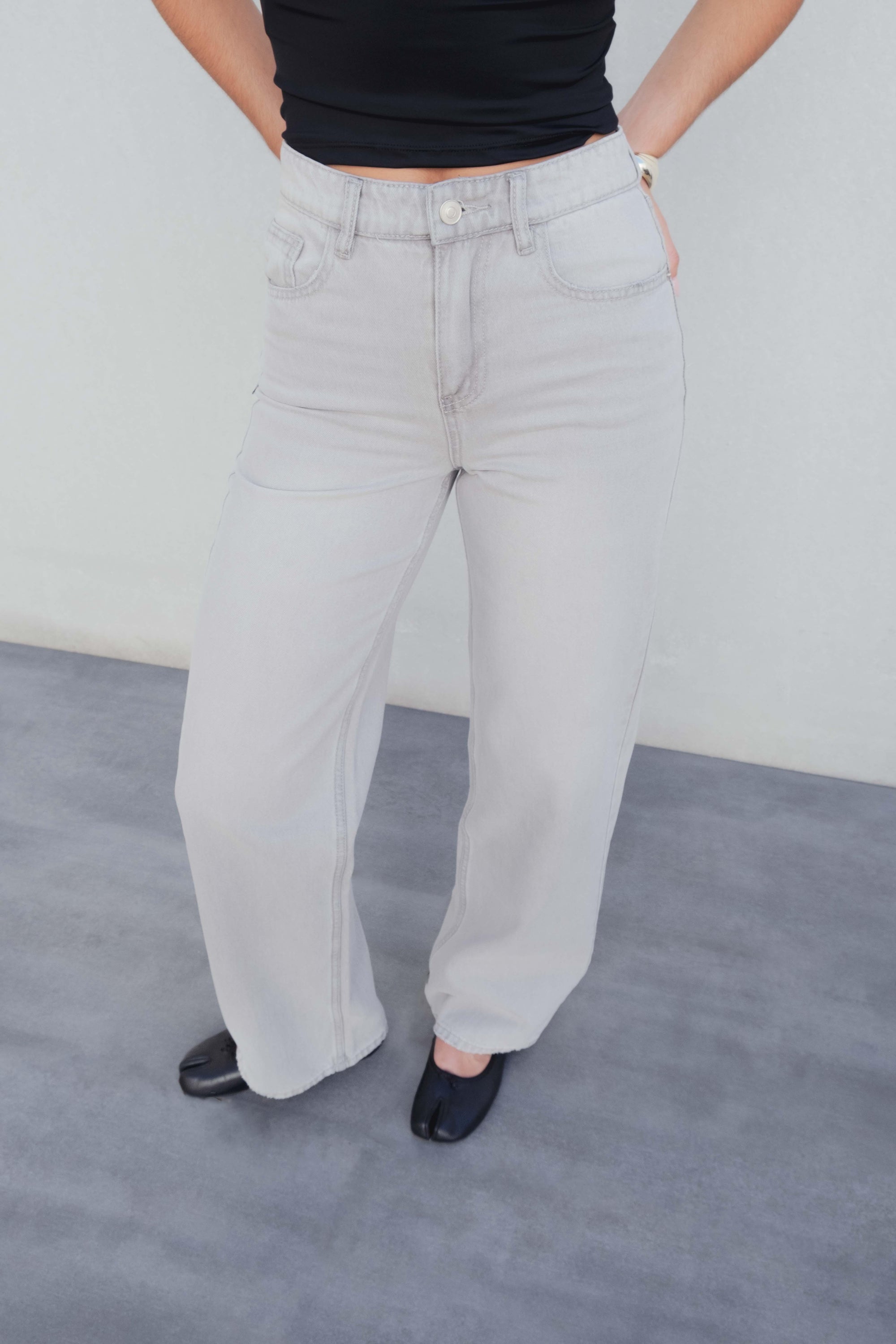 Zoom sur un jean large gris taille mi-haute, mettant en valeur sa coupe moderne et ses poches avant.