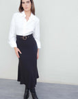 Modèle portant la jupe midi noire avec ceinture, affichant un look chic taille haute pour toutes occasions.