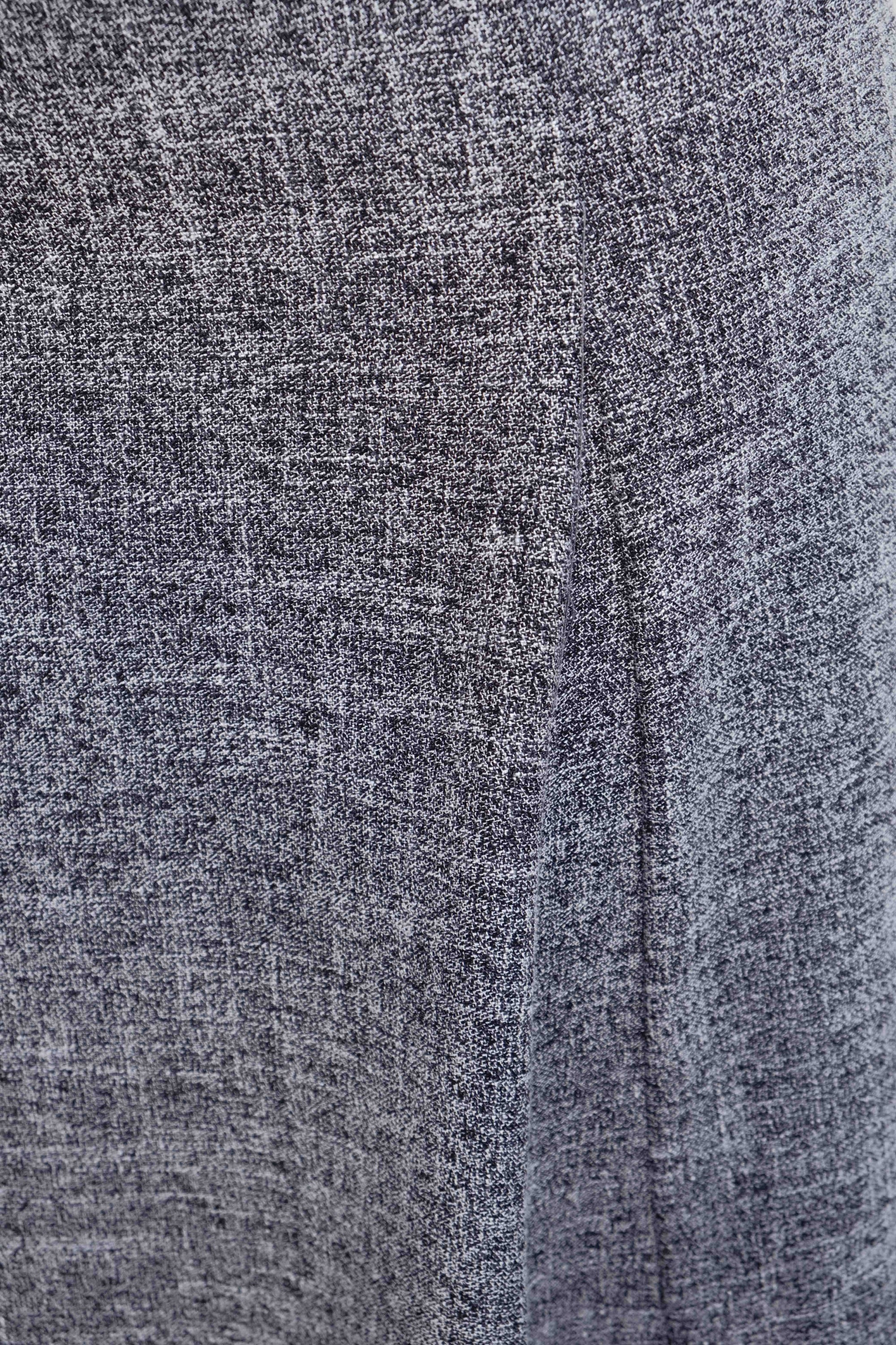 Détail du tissu d'une jupe midi structurée taille haute ceinture noire. Un style en jupe grise, offrant un mélange de confort et d'élégance.