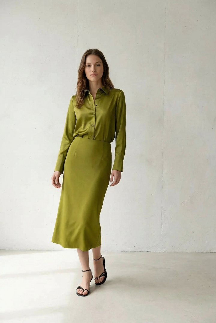 Jupe midi verte satinée portée avec une chemise verte et des sandales noires