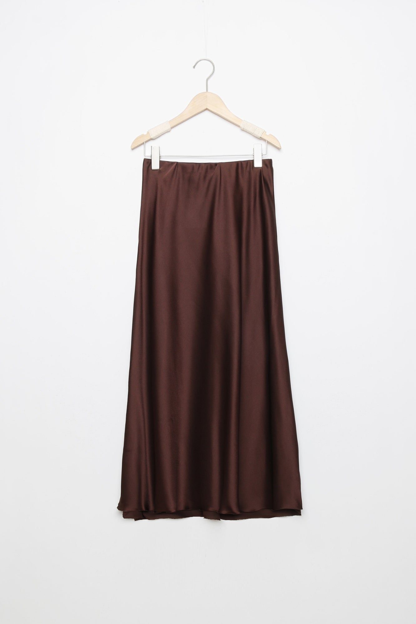 Jupe midi droite satinée en brun foncé, suspendue pour afficher la texture du tissu et la taille élastique.
