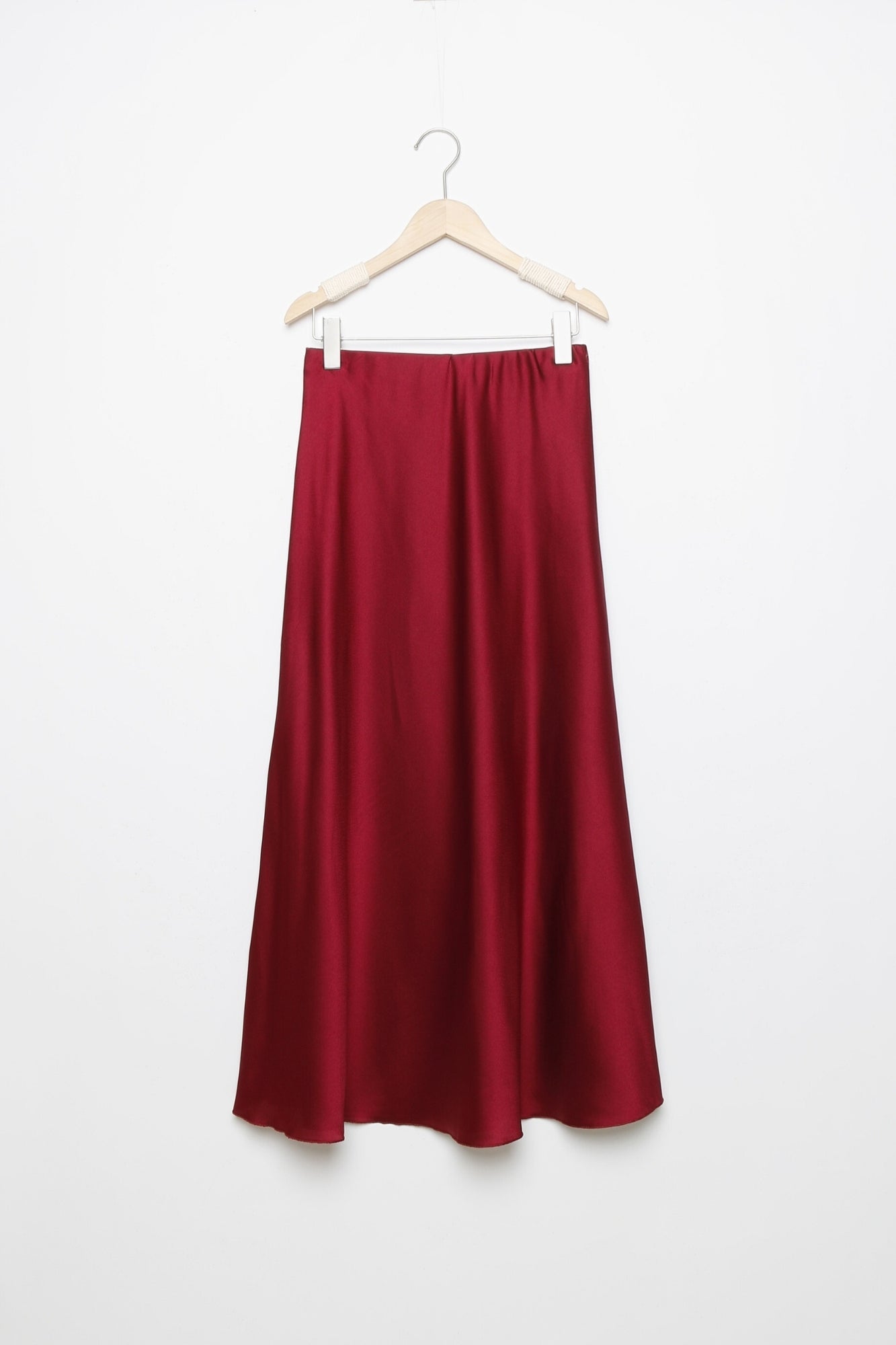 Jupe midi droite satinée en rouge, suspendue, mettant en avant sa coupe élégante et son tissu brillant.