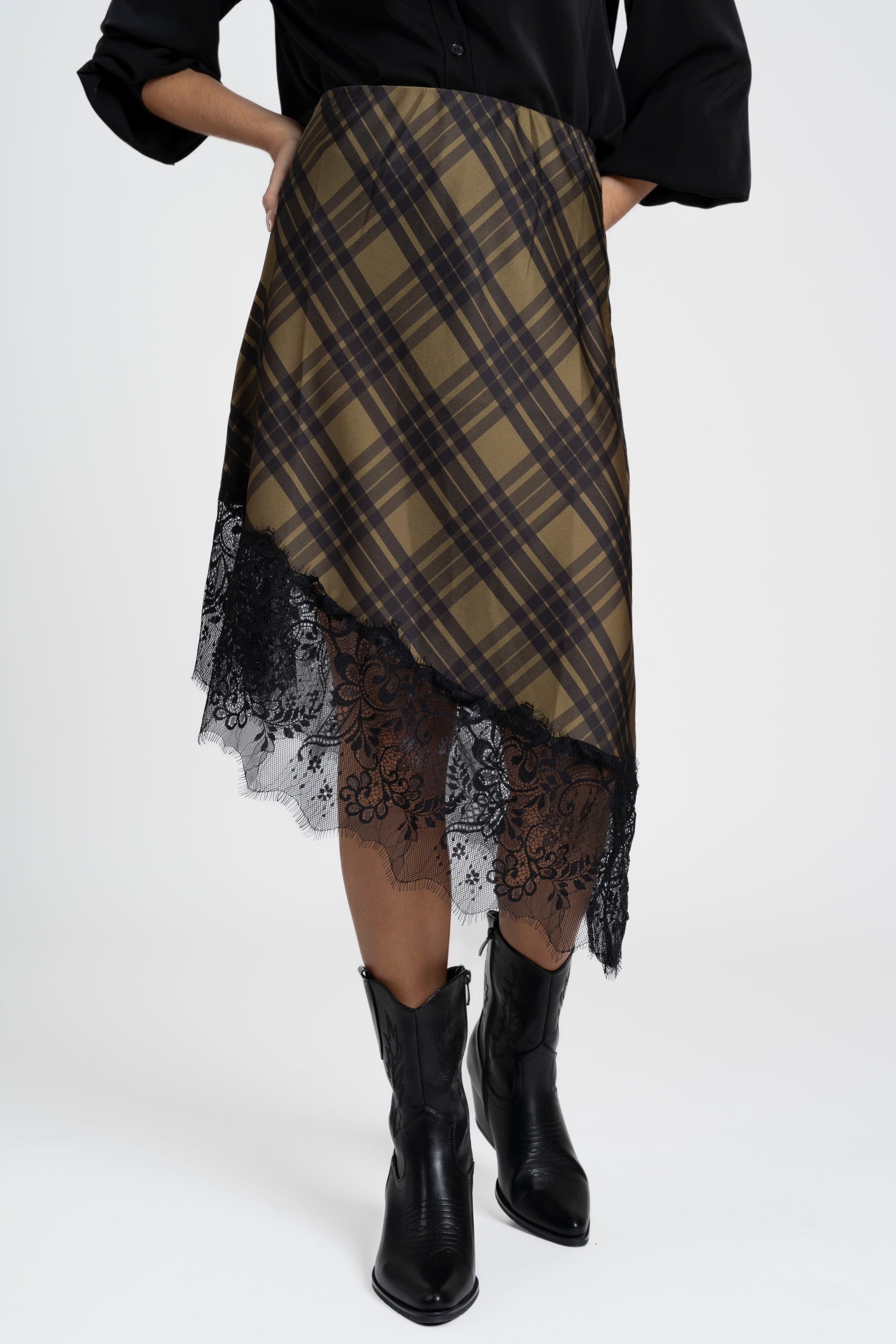 Gros plan d'une jupe midi satinée asymétrique en satin, mettant en avant le motif tartan et la délicate finition en dentelle.