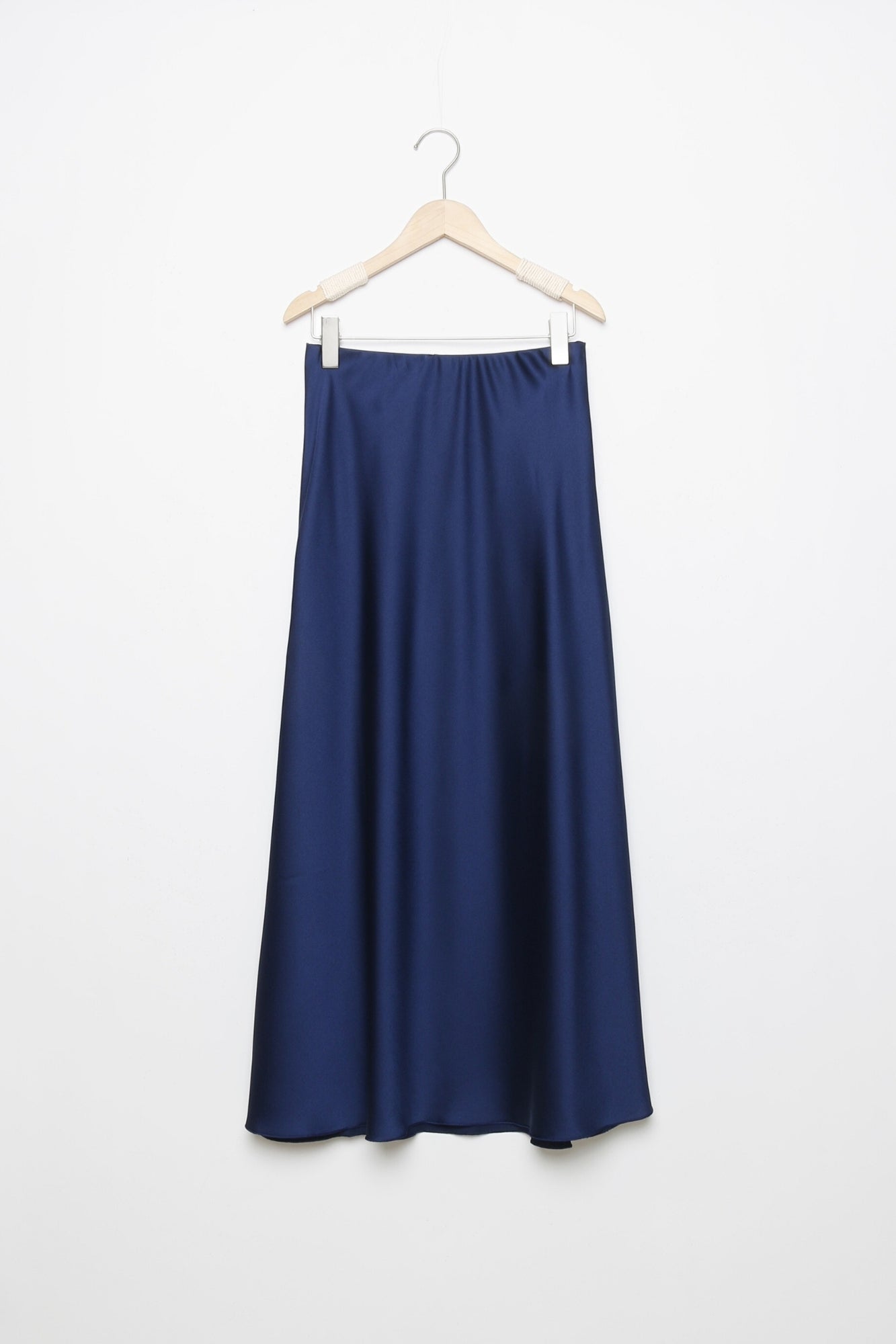 Jupe midi droite satinée en bleu marine, suspendue pour présenter la coupe élégante et le confort de la taille élastique.