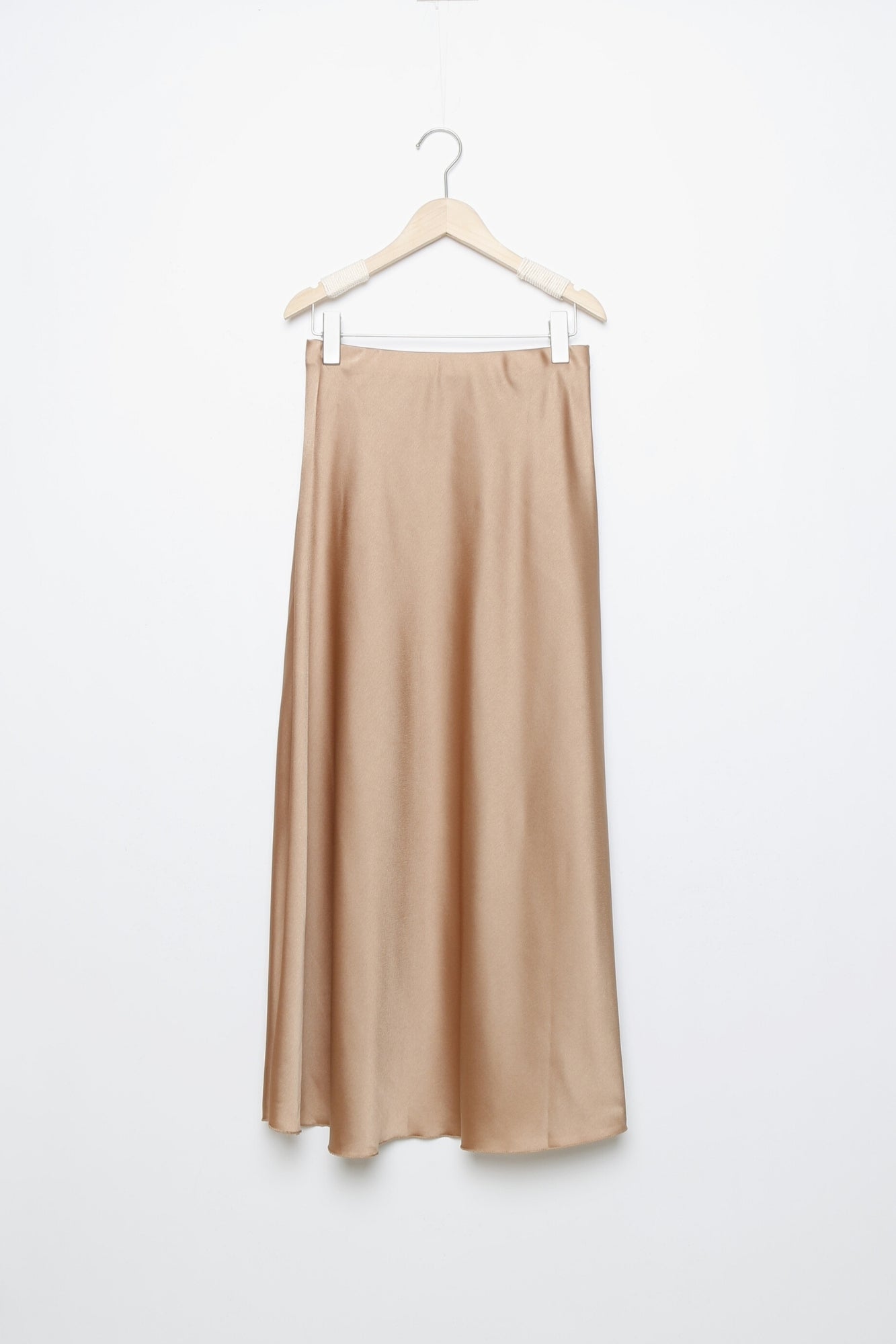 Jupe midi droite satinée couleur nude sur un cintre, parfaite pour des looks polyvalents.