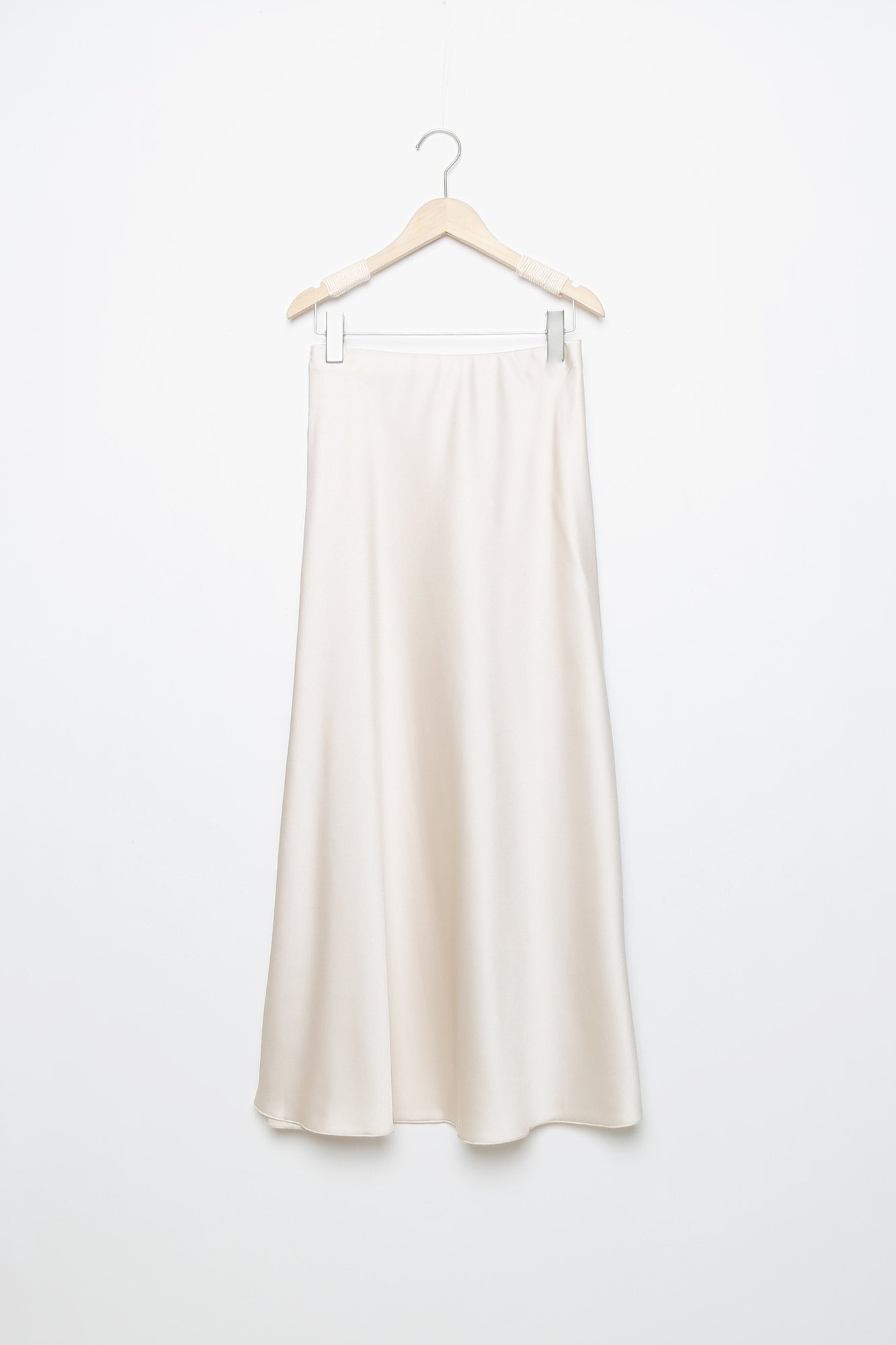Jupe midi droite satinée de couleur beige, suspendue, avec une taille élastique pour un ajustement facile.