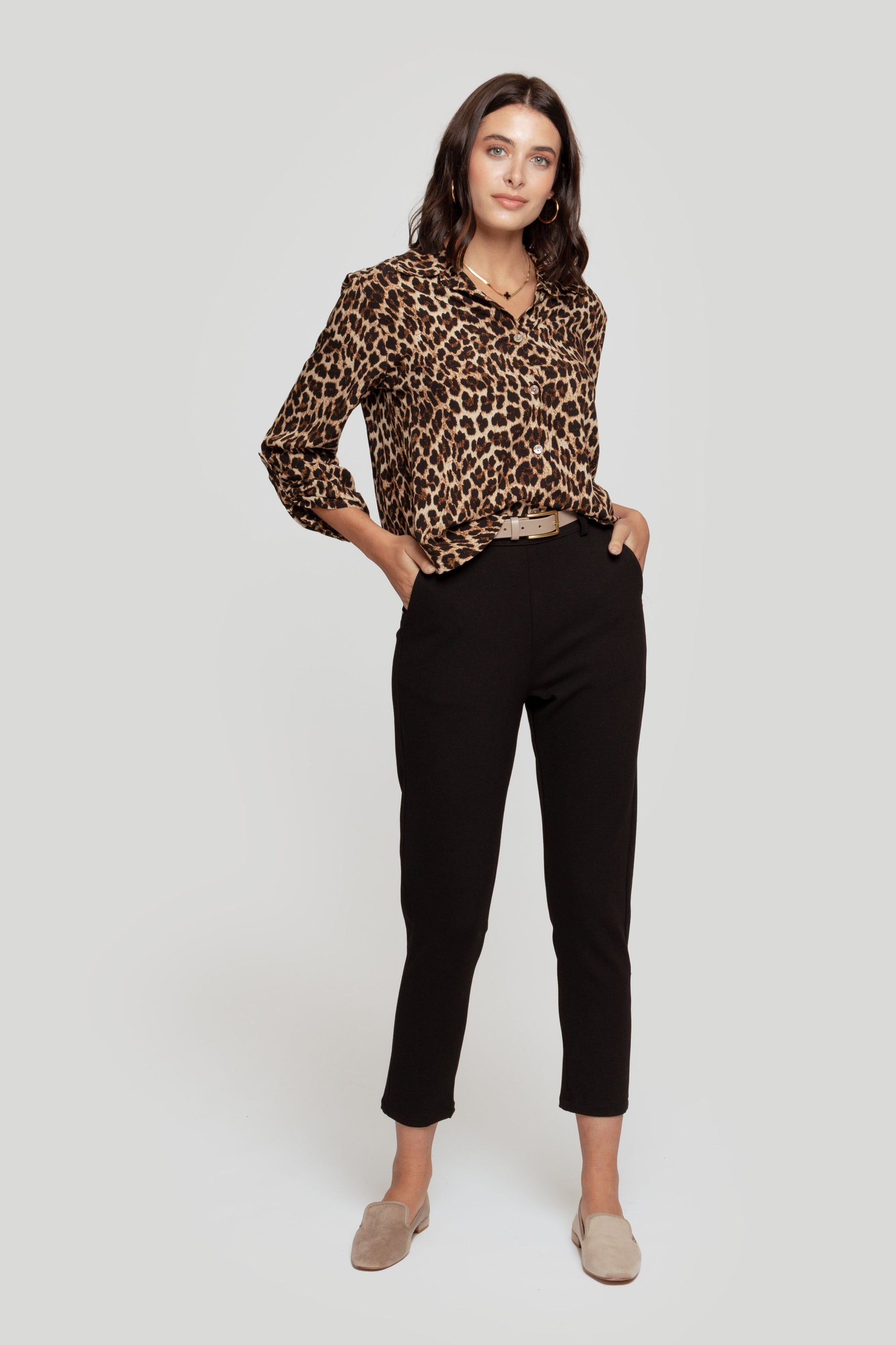 Femme en pantalon fluide taille haute noir, avec une chemise léopard, affichant un style chic.