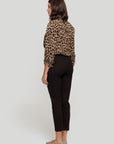 Vue arrière d'une femme portant un pantalon fluide taille haute noir, stylée avec une chemise léopard.