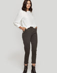 Femme en pantalon fluide taille haute gris, stylée avec un haut blanc, affichant un look contemporain.