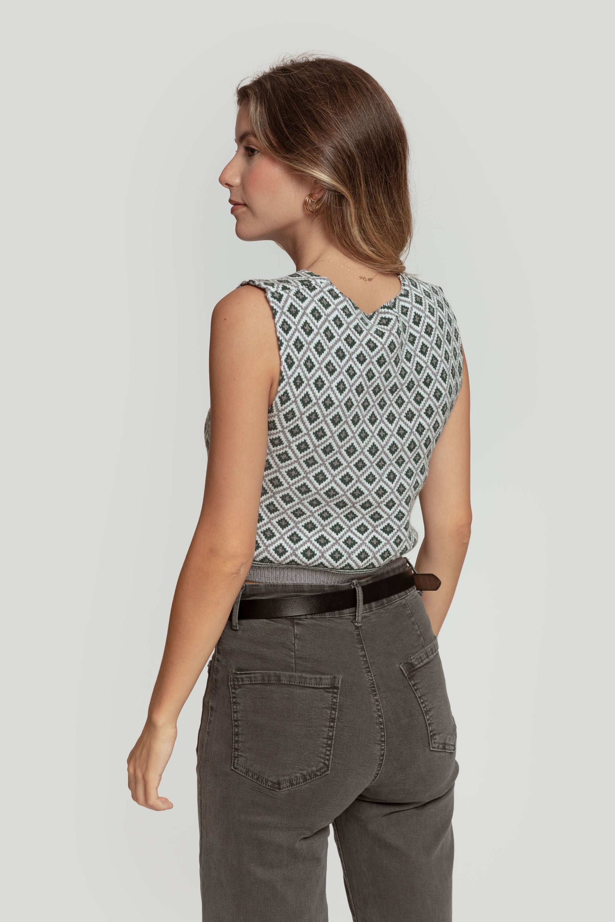 Vue arrière d'une femme portant un gilet femme en maille sans manches géométrique, complétant sa tenue avec un pantalon gris.