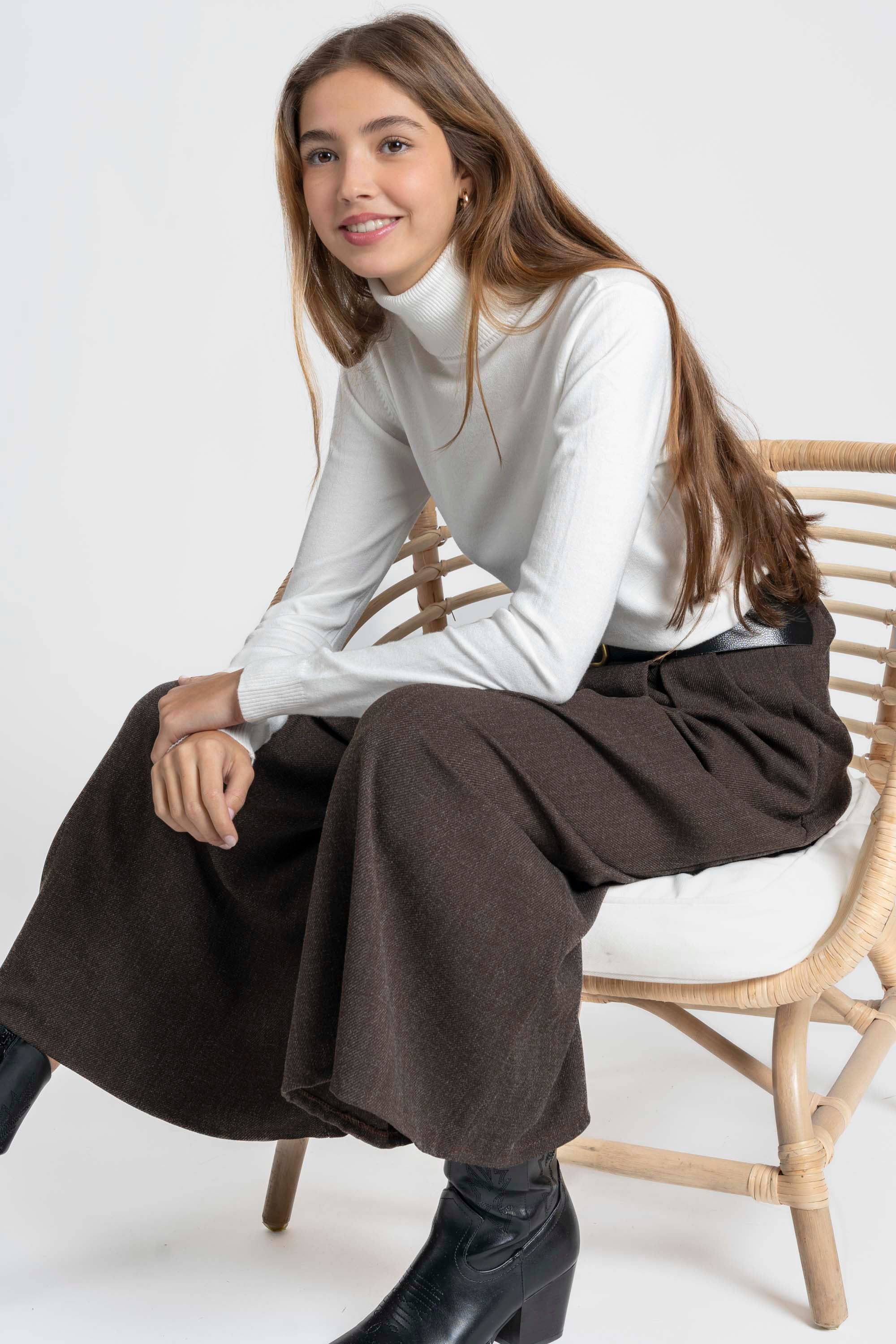 Femme assise sur une chaise avec un pantalon large taille haute femme, combiné avec un haut blanc, montrant un style élégant et décontracté.