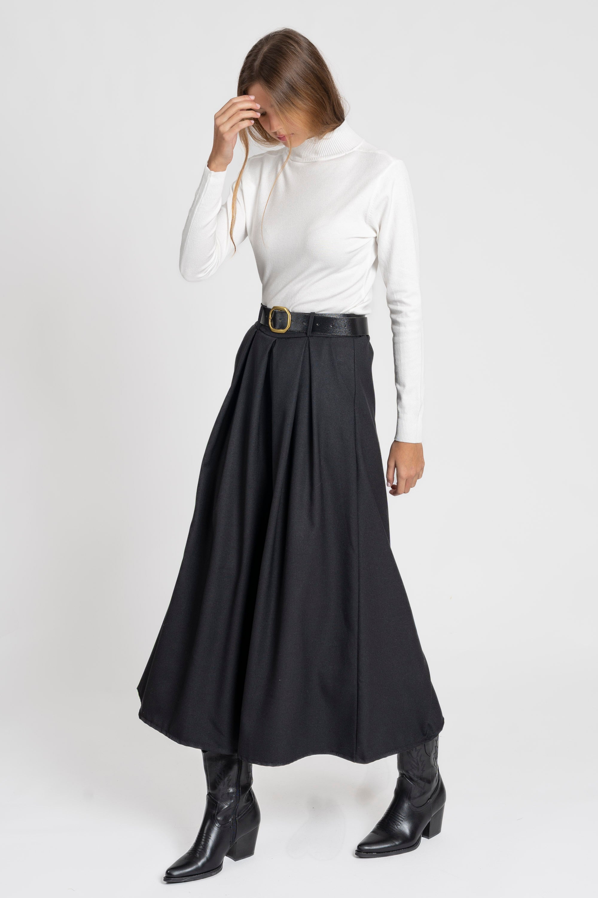 Femme en train de se passer la main dans les cheveux, avec un pantalon large taille haute femme en noir.