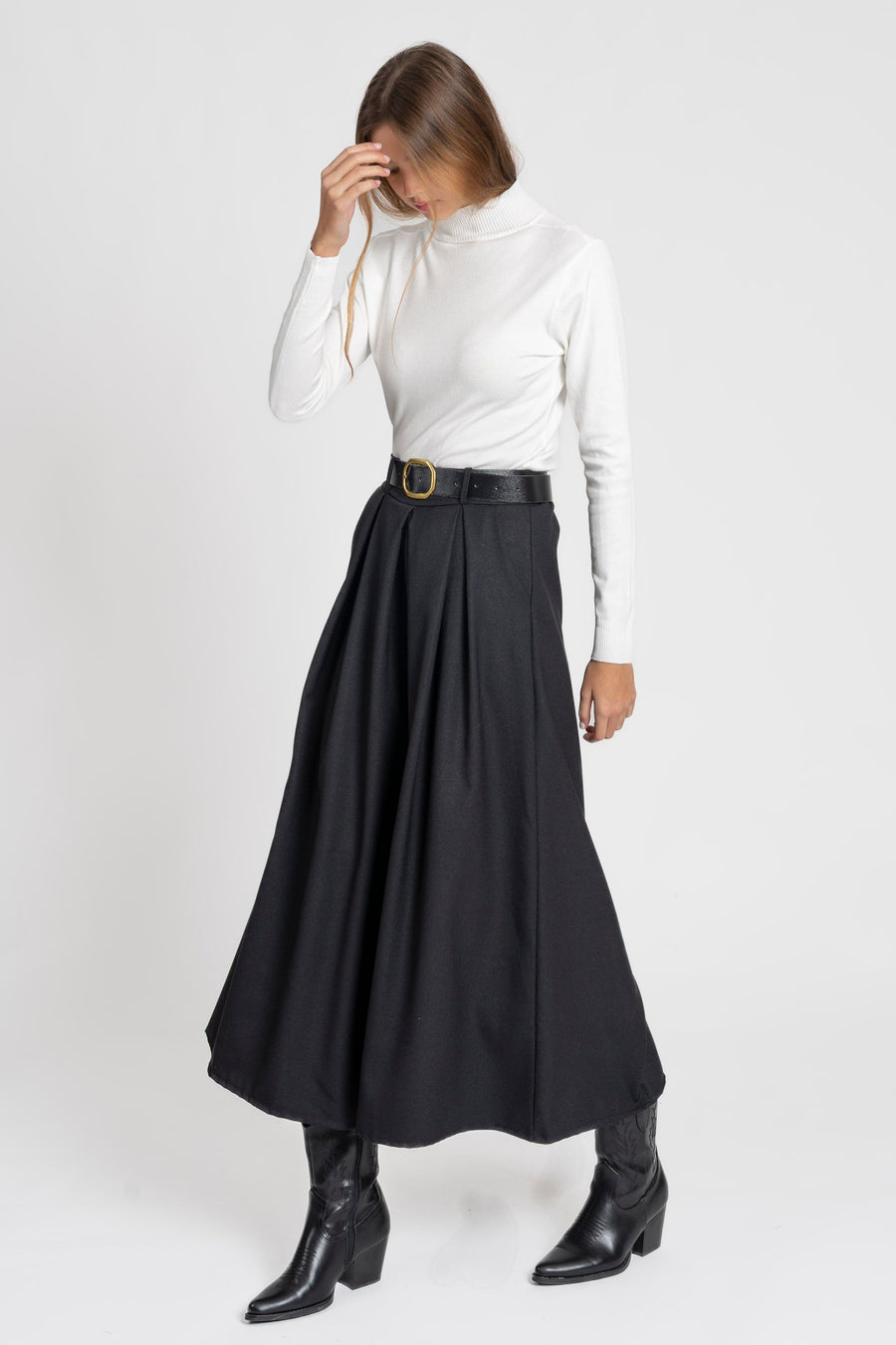 Femme en train de se passer la main dans les cheveux, avec un pantalon large taille haute femme en noir.