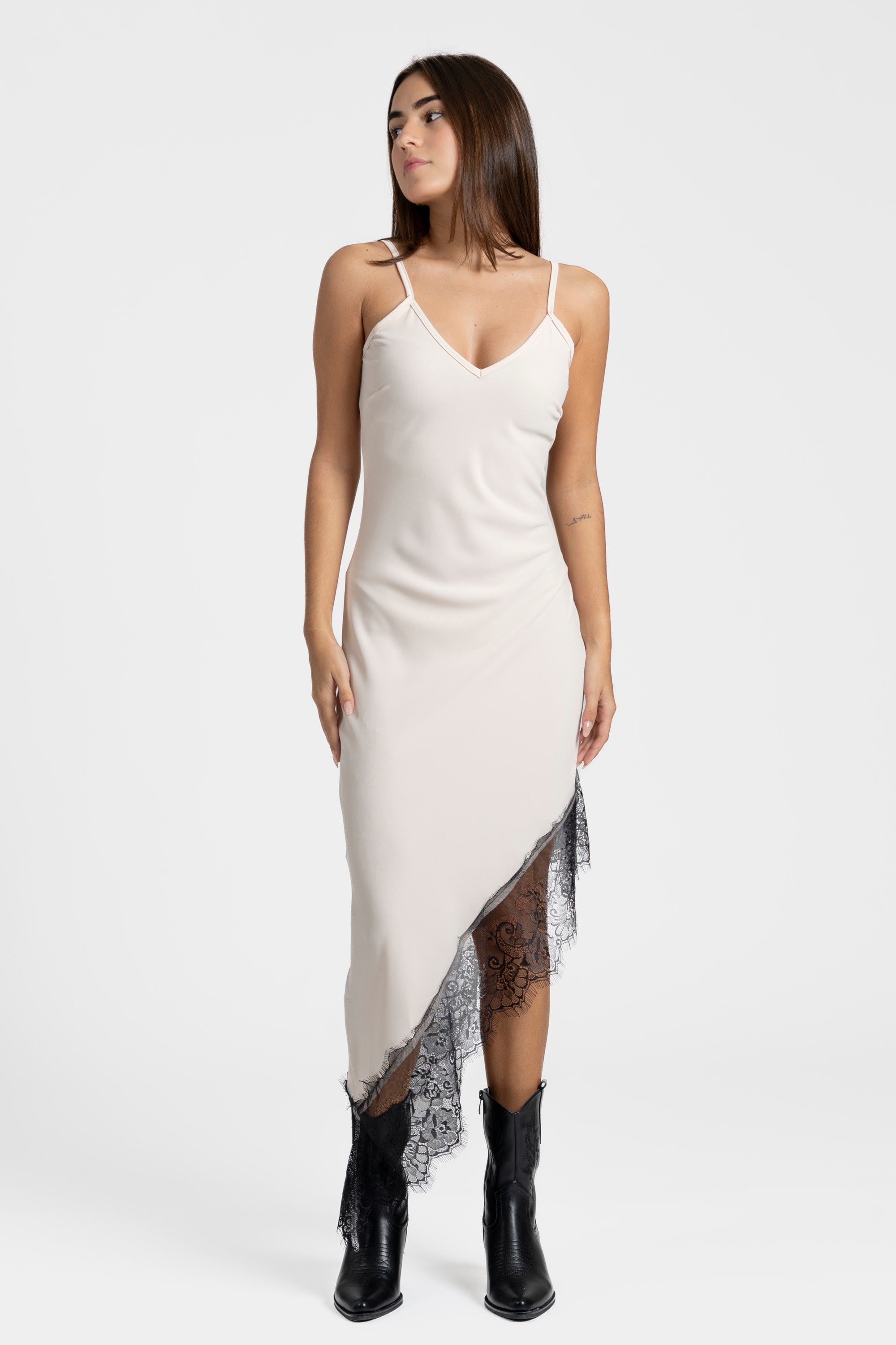 Modèle portant une robe asymétrique dentelle Bretelles fines Tissu extensible en beige, mettant en valeur le détail en dentelle sur le bas.