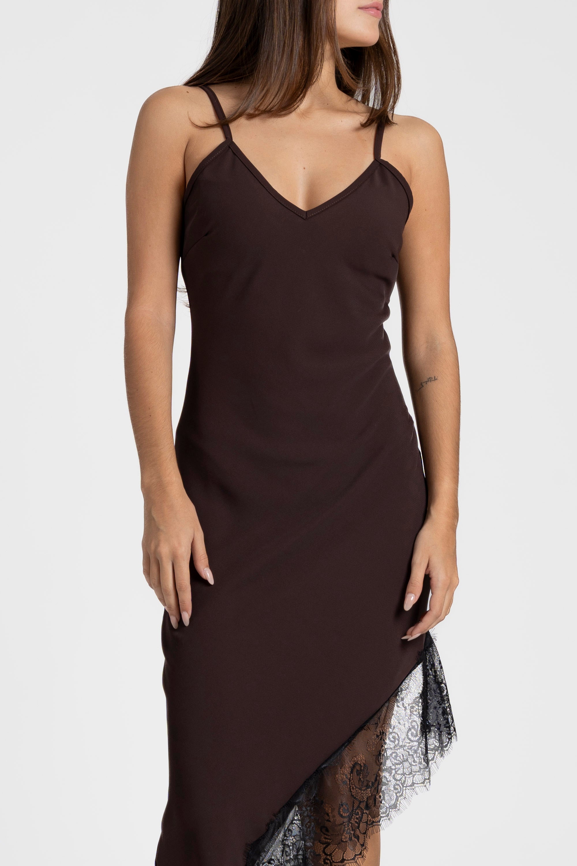 Femme affichant une robe asymétrique dentelle Bretelles fines Tissu extensible, en brun, combinée avec des bottes élégantes.