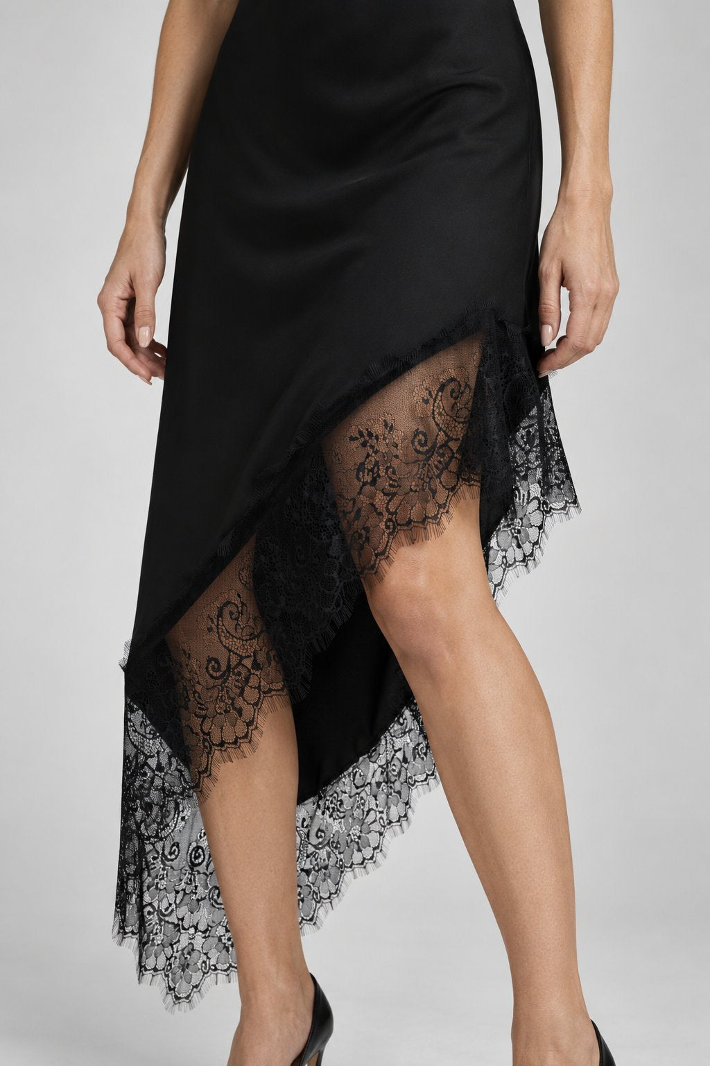 Focus sur une robe asymétrique dentelle Bretelles fines Tissu extensible en noir, montrant le détail délicat en dentelle en bas.