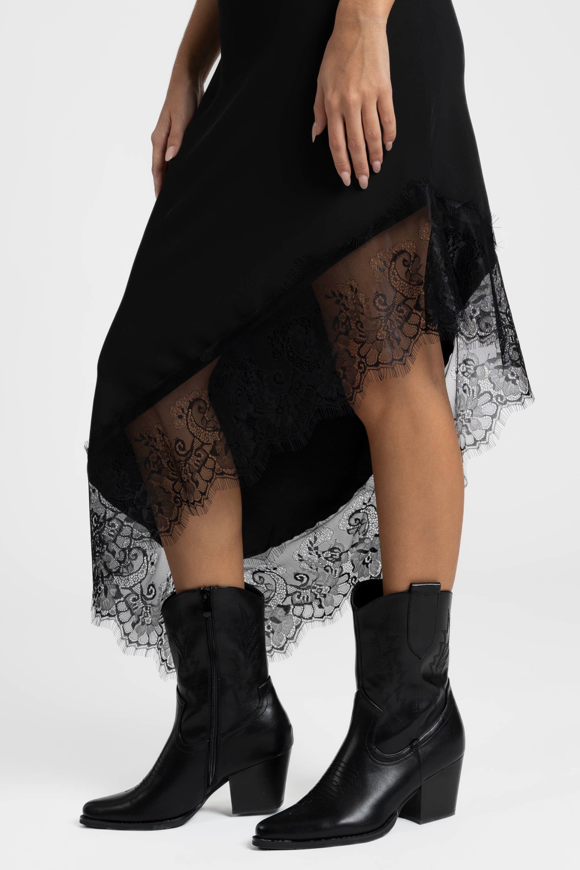 Focus sur une robe asymétrique dentelle Bretelles fines Tissu extensible en noir, montrant le détail délicat en dentelle en bas.