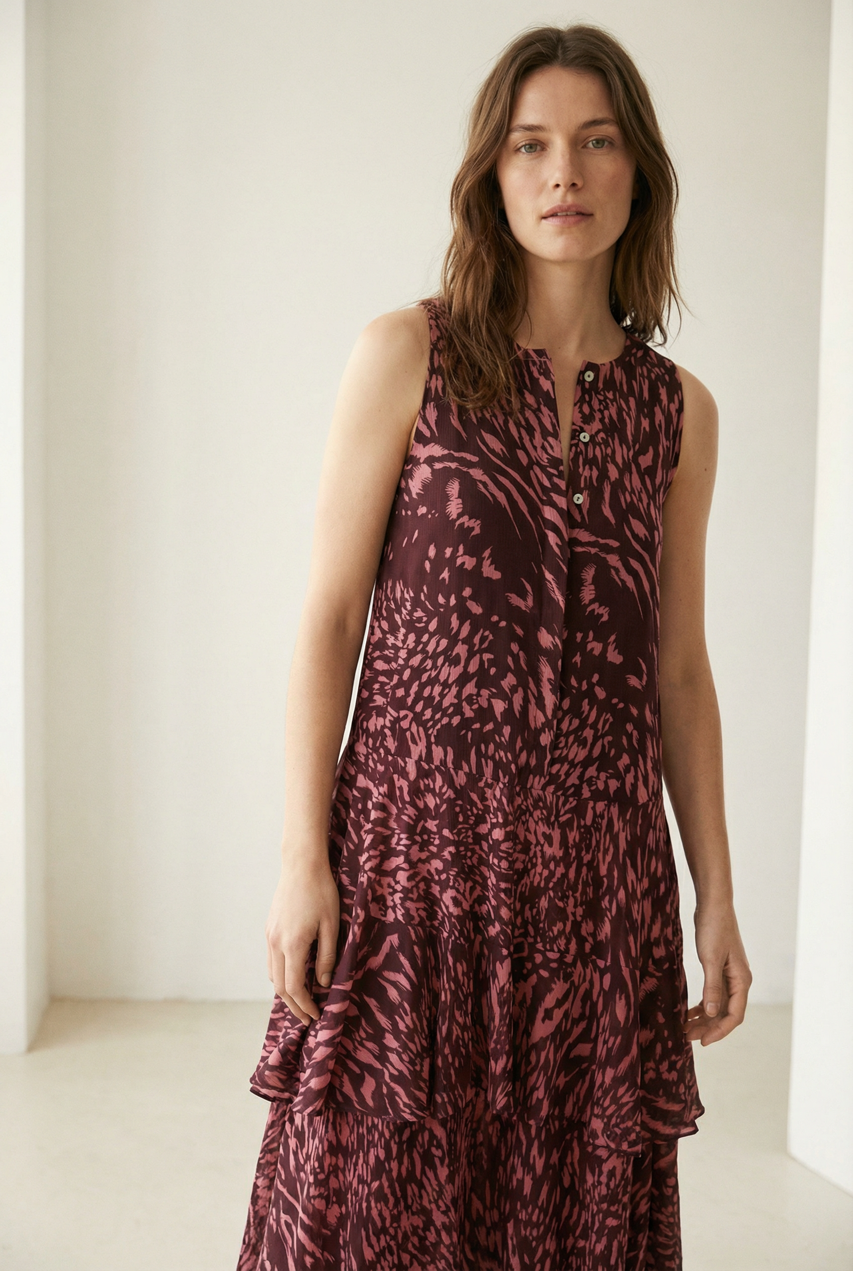 Robe longue imprimée à volants sans manches marron, modèle femme, prise de profil mettant en valeur la fluidité du tissu.