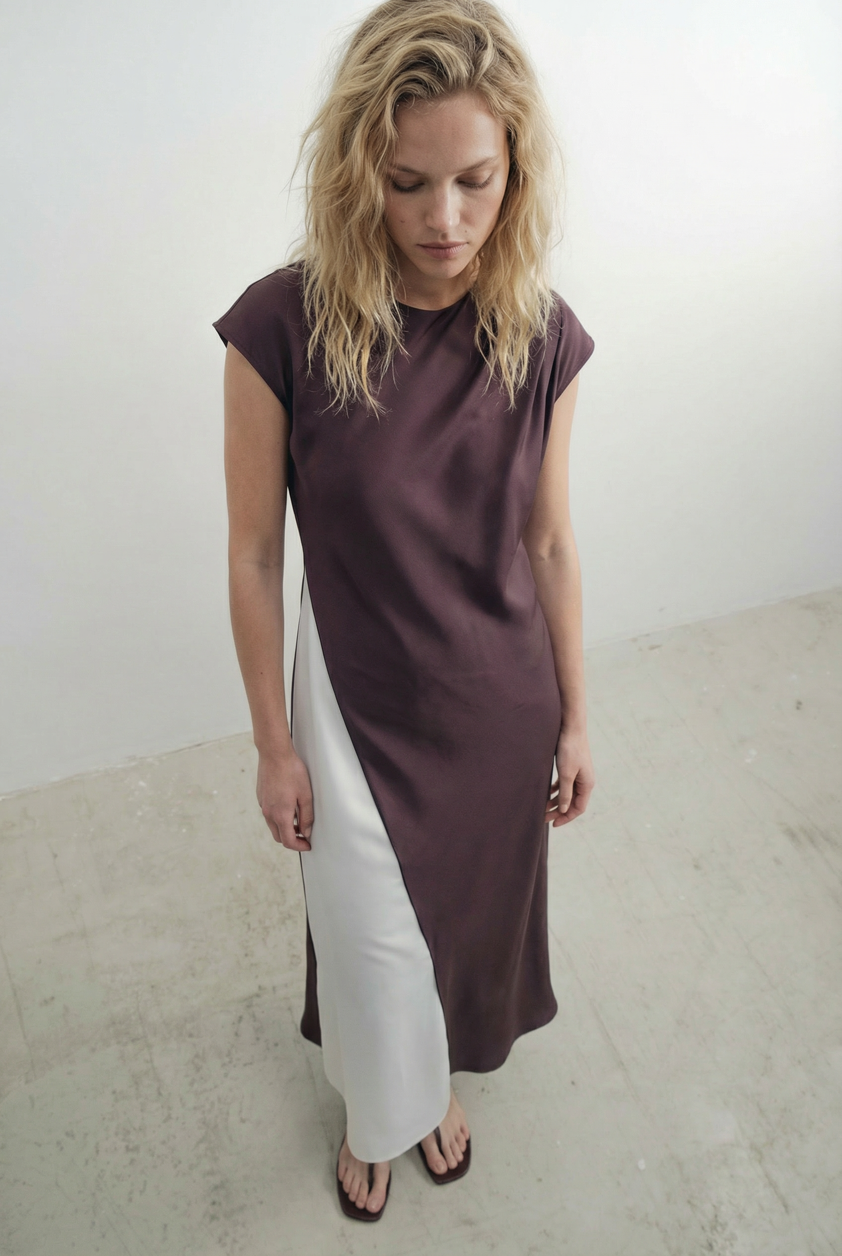 Femme en pose mettant en valeur la robe midi marron élégante, à col rond et sans manches, idéale pour diverses occasions.