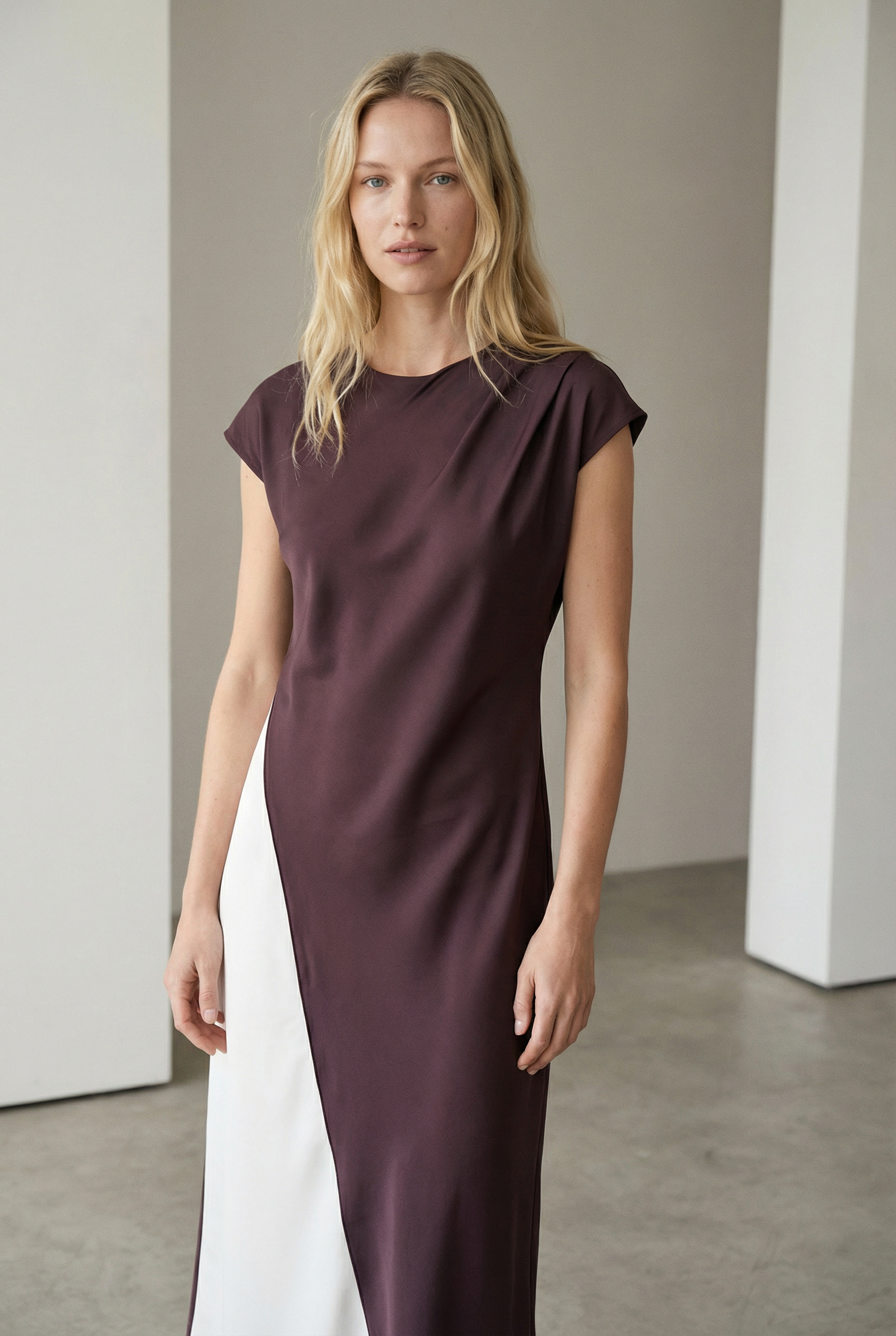 Femme souriante dans une robe midi marron élégante à col rond sans manches, mettant en avant le confort et le style chic de cette pièce.