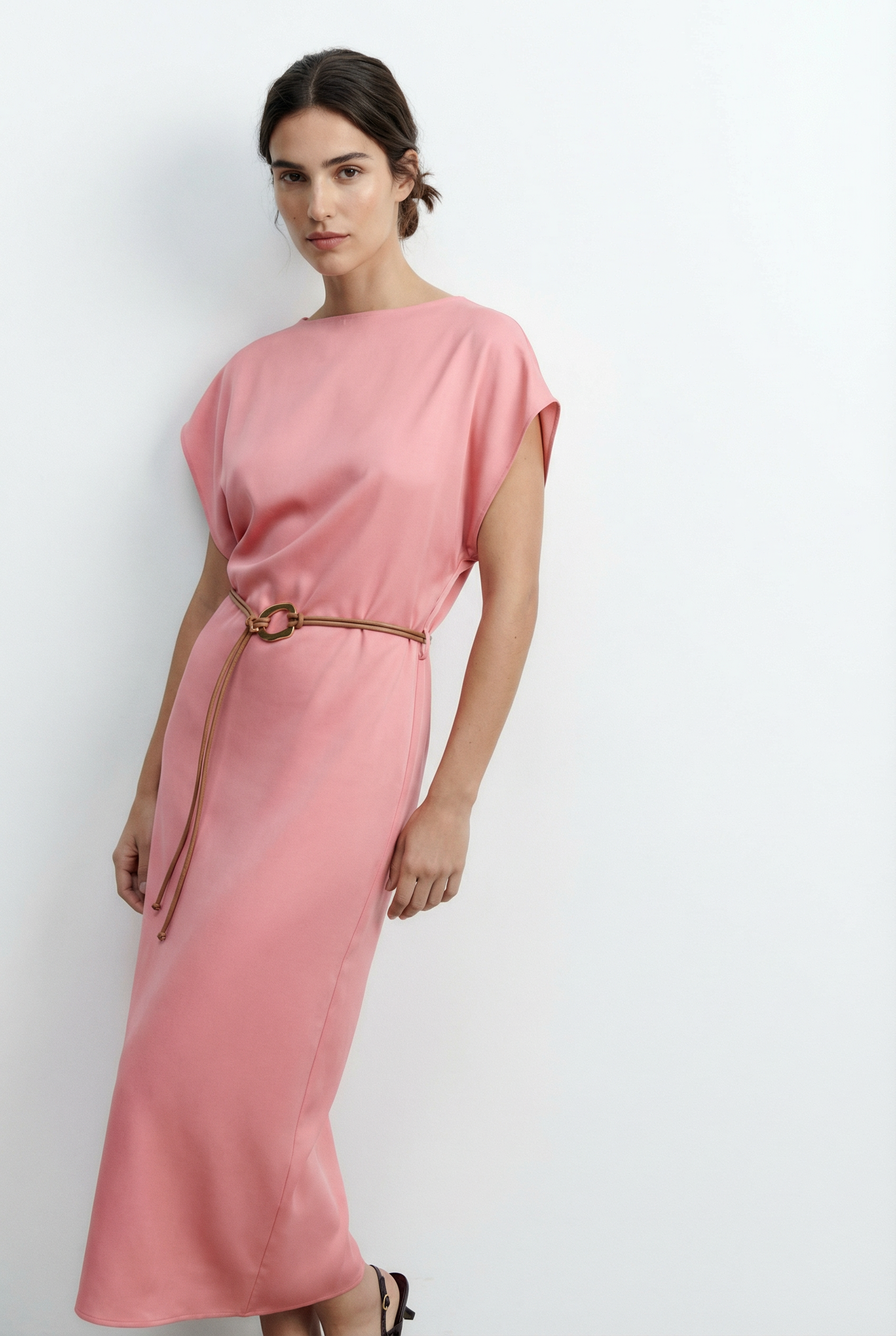 Modèle portant une robe midi satinée avec ceinture fine couleur rose, parfaite pour un style chic et décontracté.
