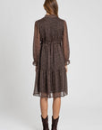 Vue arrière d'une femme en robe midi fluide marron imprimée avec des pois, style à cordon et manches longues. Parfaite pour les soirées ou les journées décontractées. Robe pois marron.