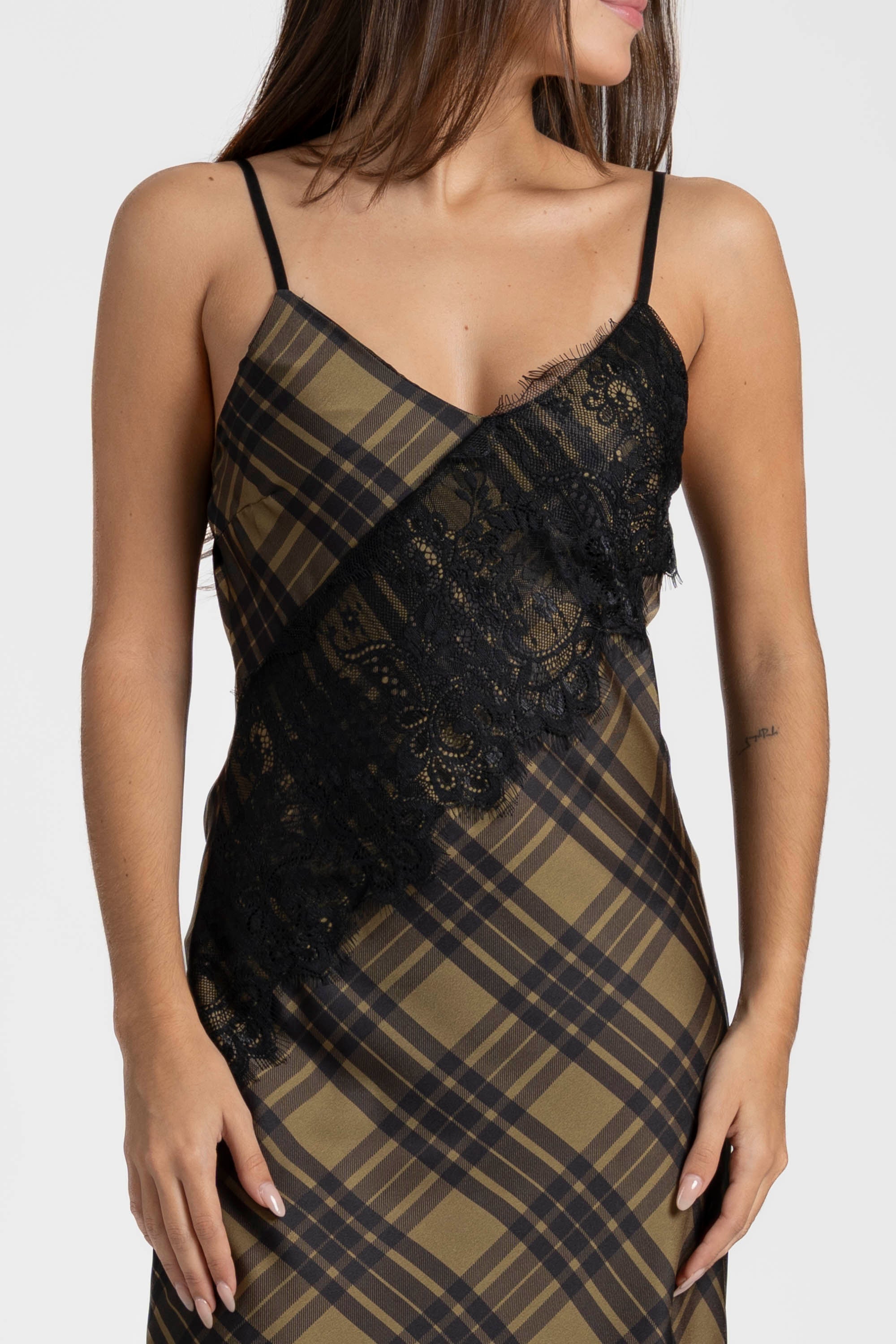 Gros plan sur la robe satin asymétrique mettant en avant la dentelle délicate noire et le motif à carreaux, illustrant le décolleté en V.