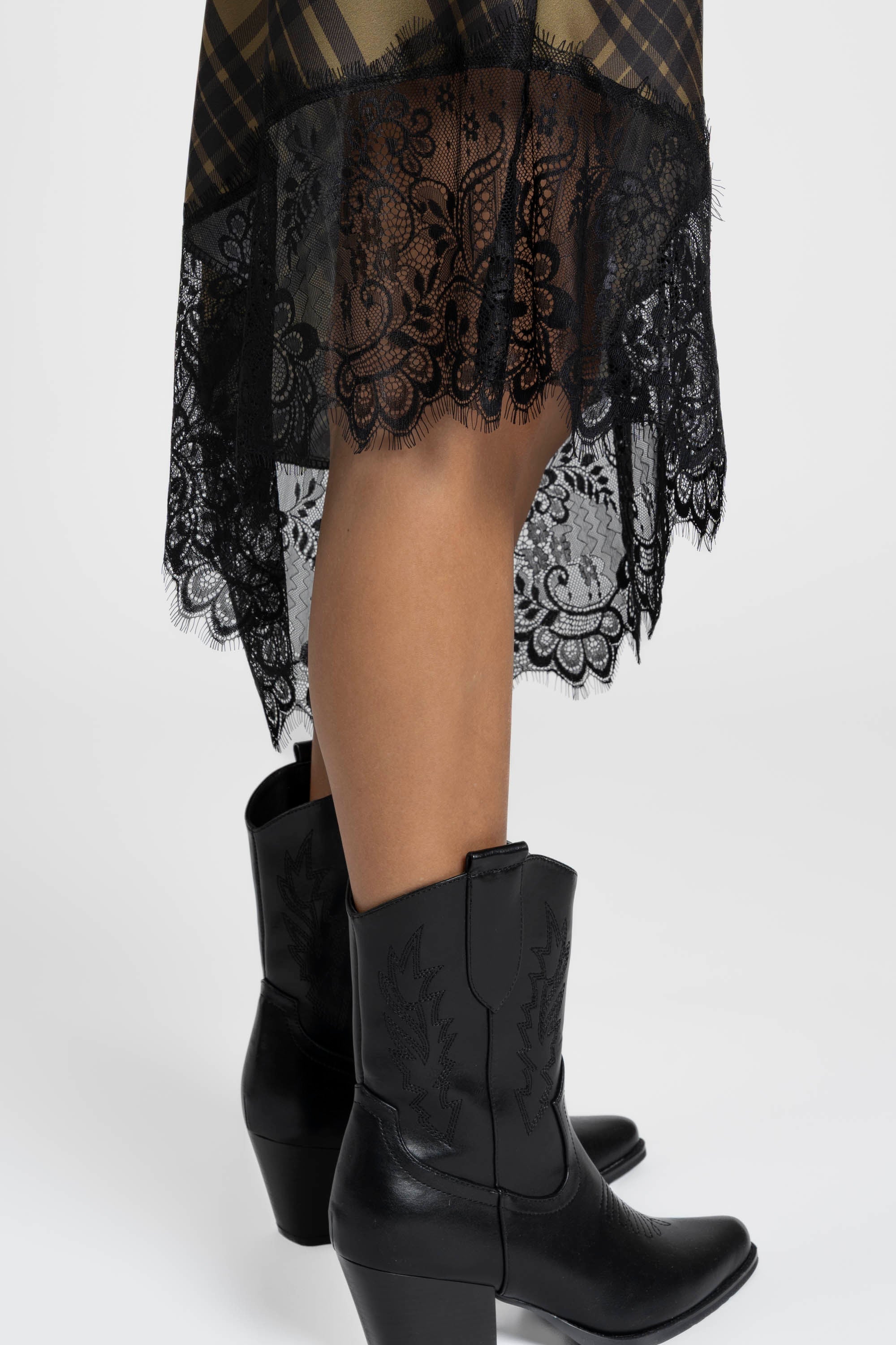 Détail du bas de la robe satin asymétrique avec dentelle, révélant son élégance et son design moderne.