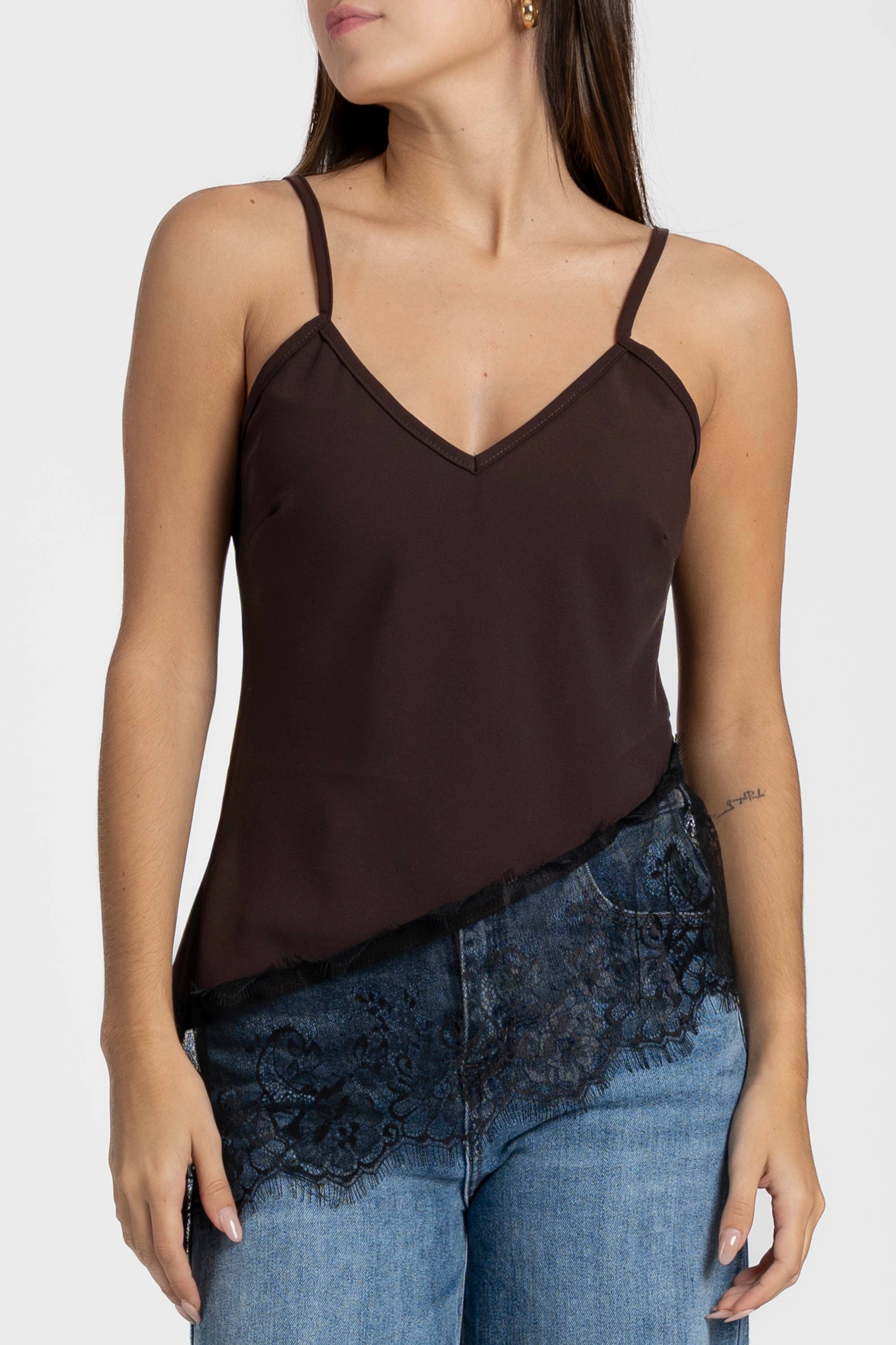 Détail du top dentelle marron, bretelles fines et tissu texturé sur un jean.